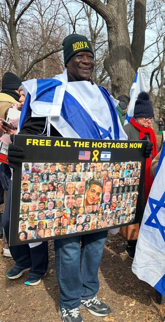 Simon Deng, a former child slave from South Sudan, holding a sign at a Central Park rally in solidarity with his Jewish brothers and sisters