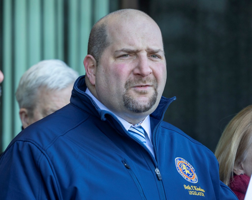 Nassau County legislitor Seth Koslow in a blue jacket standing with a coalition of Nassau County legislators and civil rights attorneys announcing a lawsuit in Mineola, New York