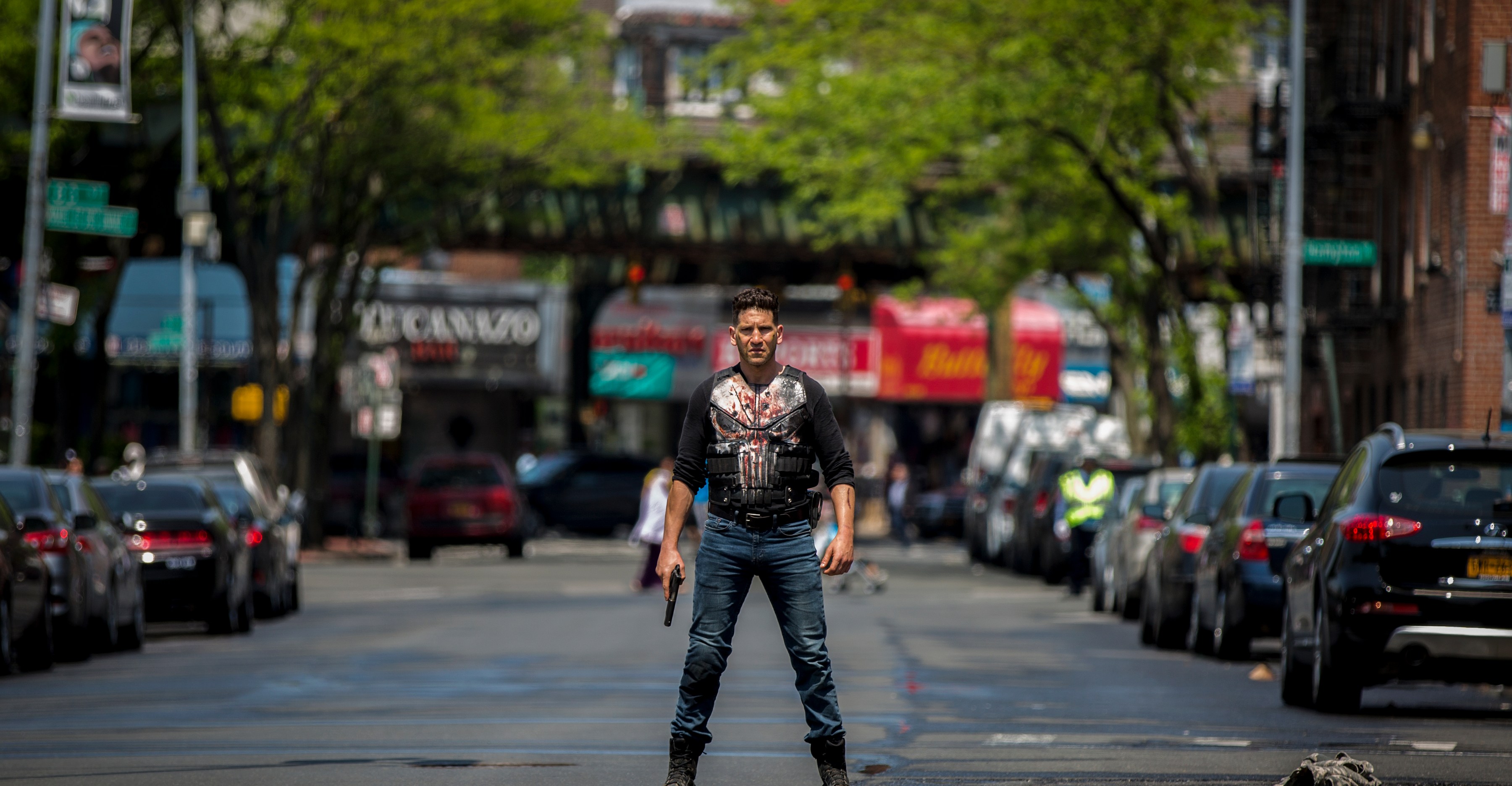 Jon Bernthal as The Punisher standing in the middle of a New York street with a bloody t-shirt