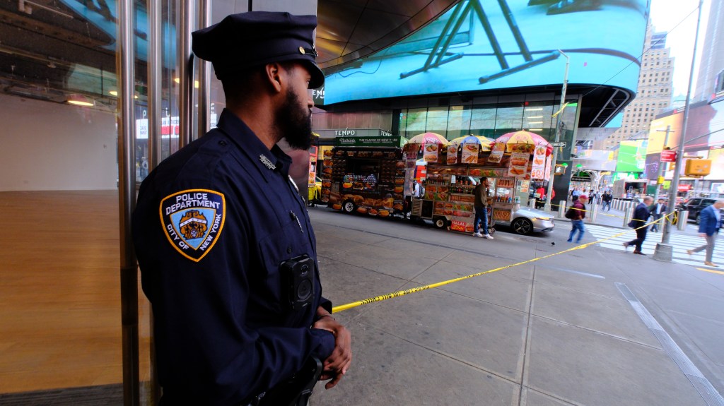 NYPD officer securing crime scene at the corner of 47th Street and 7th Avenue after a street cart vendor was grazed by a bullet