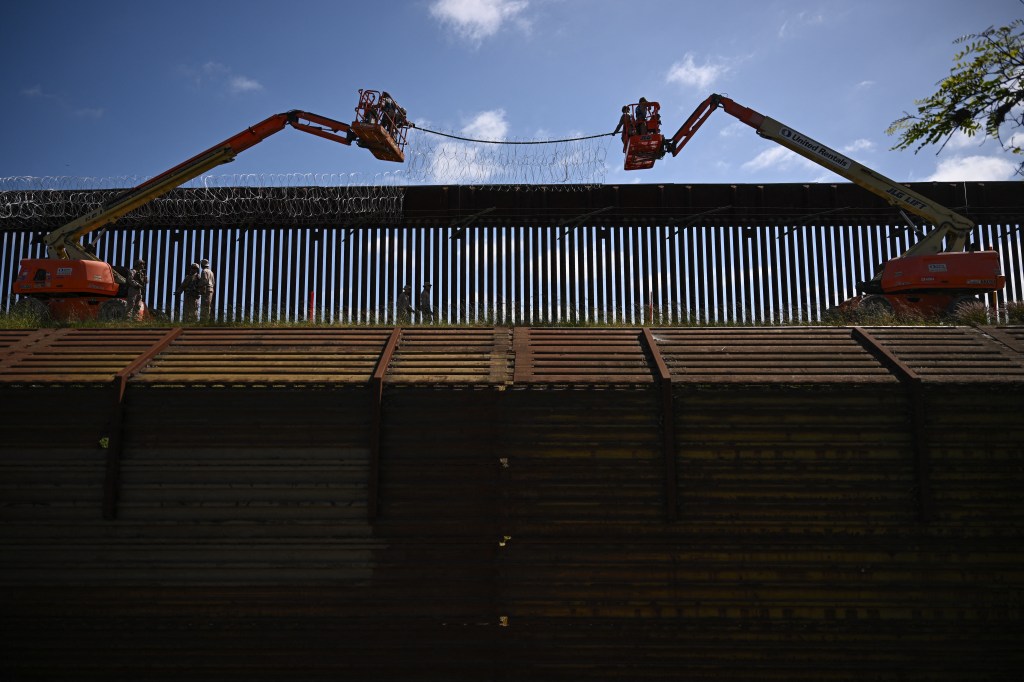 US military personnel install concertina wire on top of the wall along the US-Mexico border between San Diego and Tijuana.