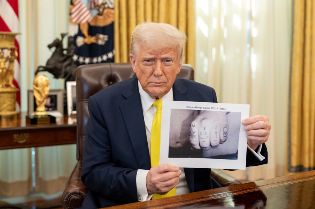 President Trump holding a photo of Abrego Garcia's tattoos on his knuckles.