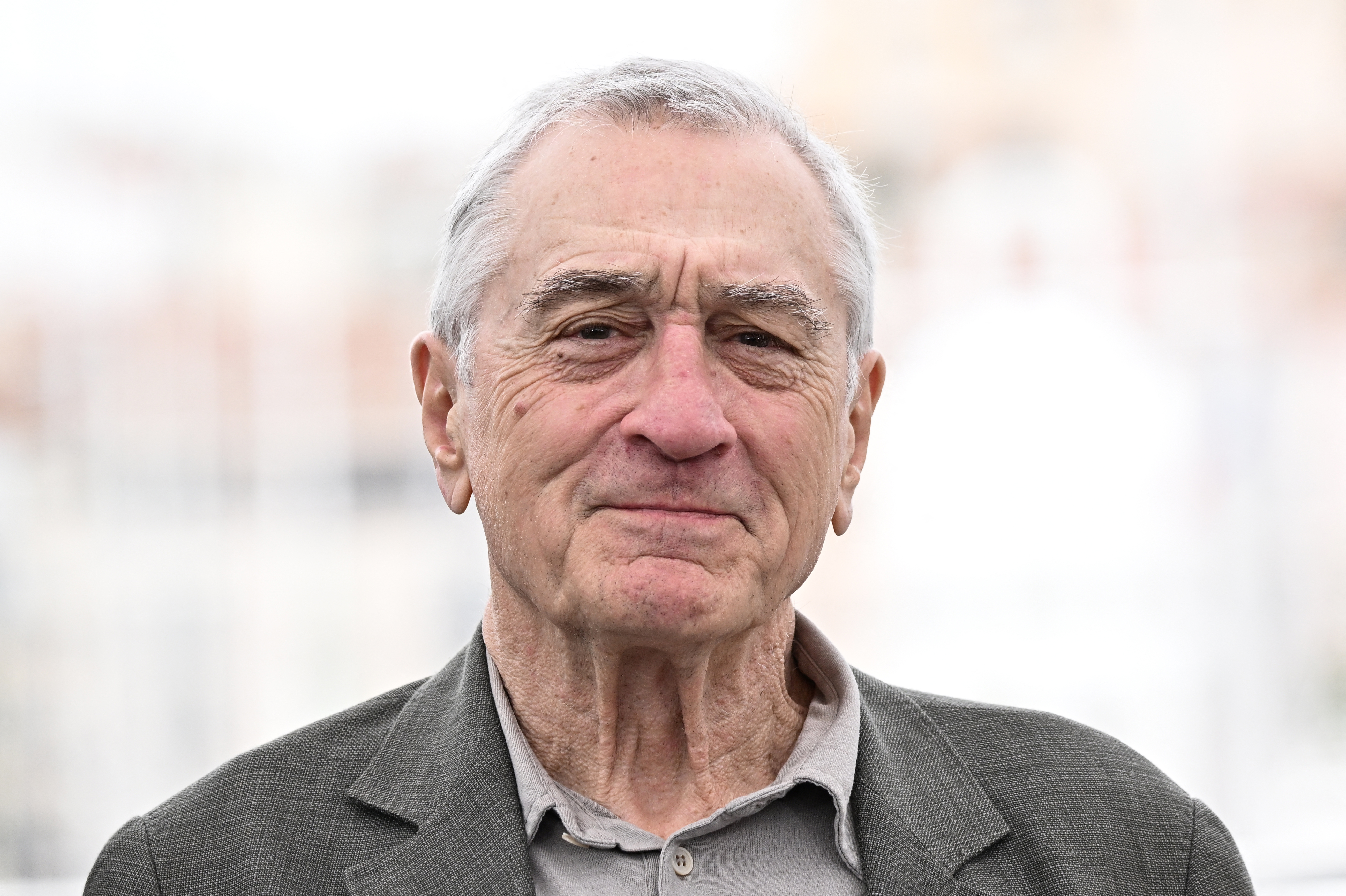 Robert De Niro smiles outdoors. 