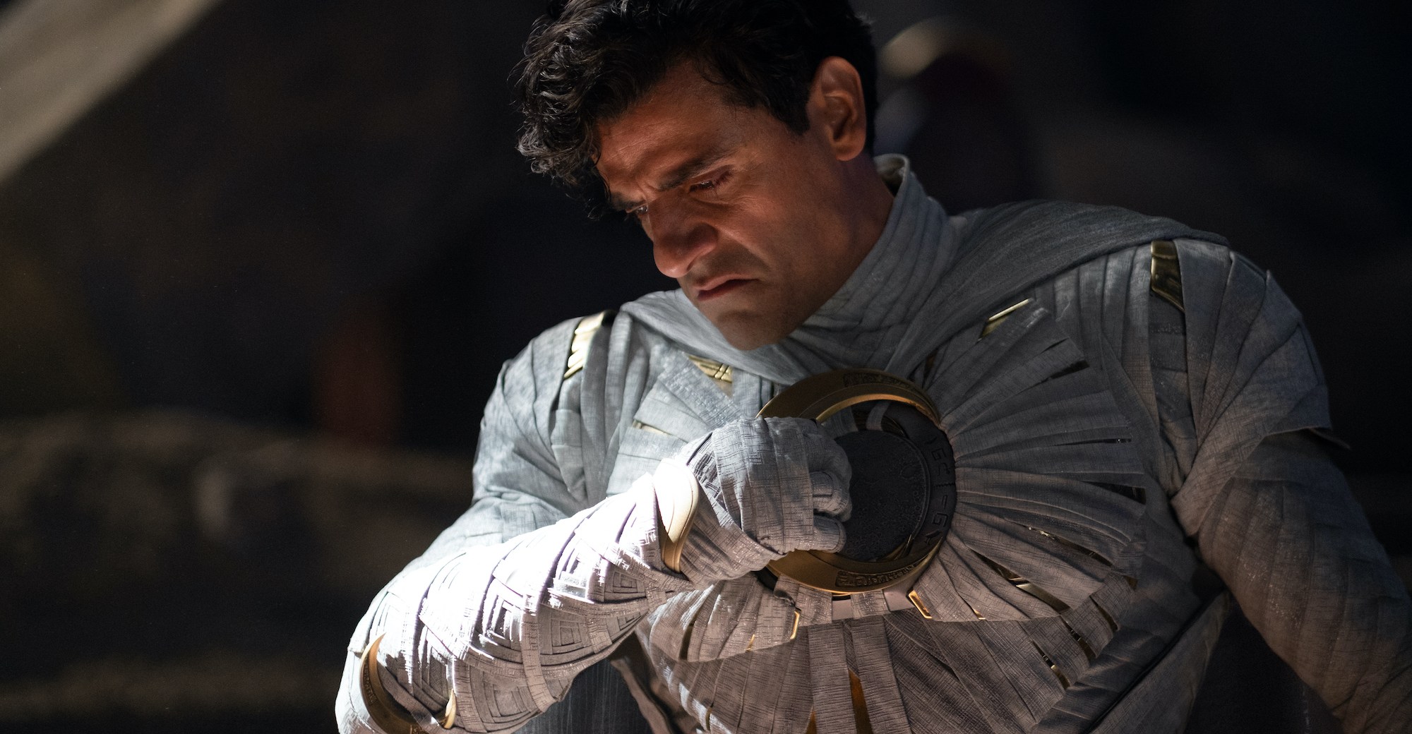 Marc Spector unmasked in the Moon Knight costume, pulling a crescent blade from his chest.