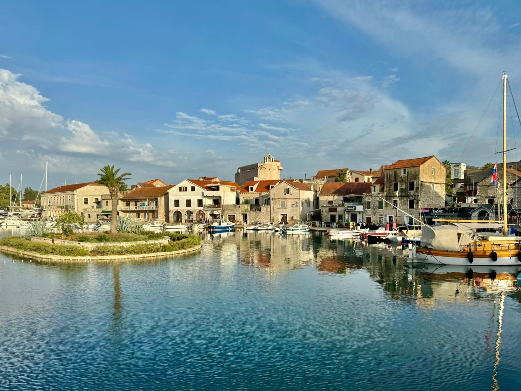 View of Vrboska buildings along water and docked boats from the water