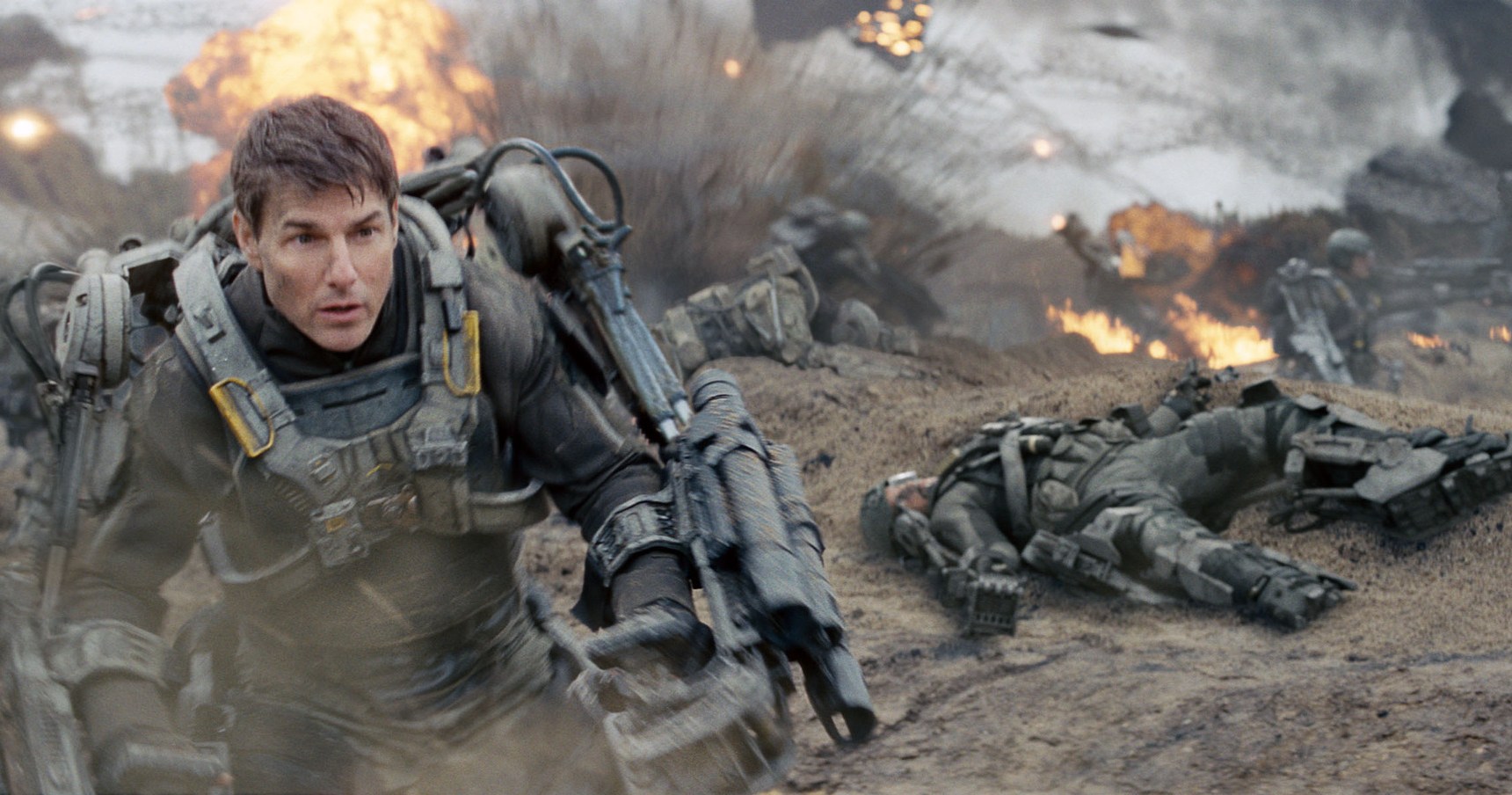 Tom Cruise as Cage in power armor storming a beach filled with explosions in Edge of Tomorrow.