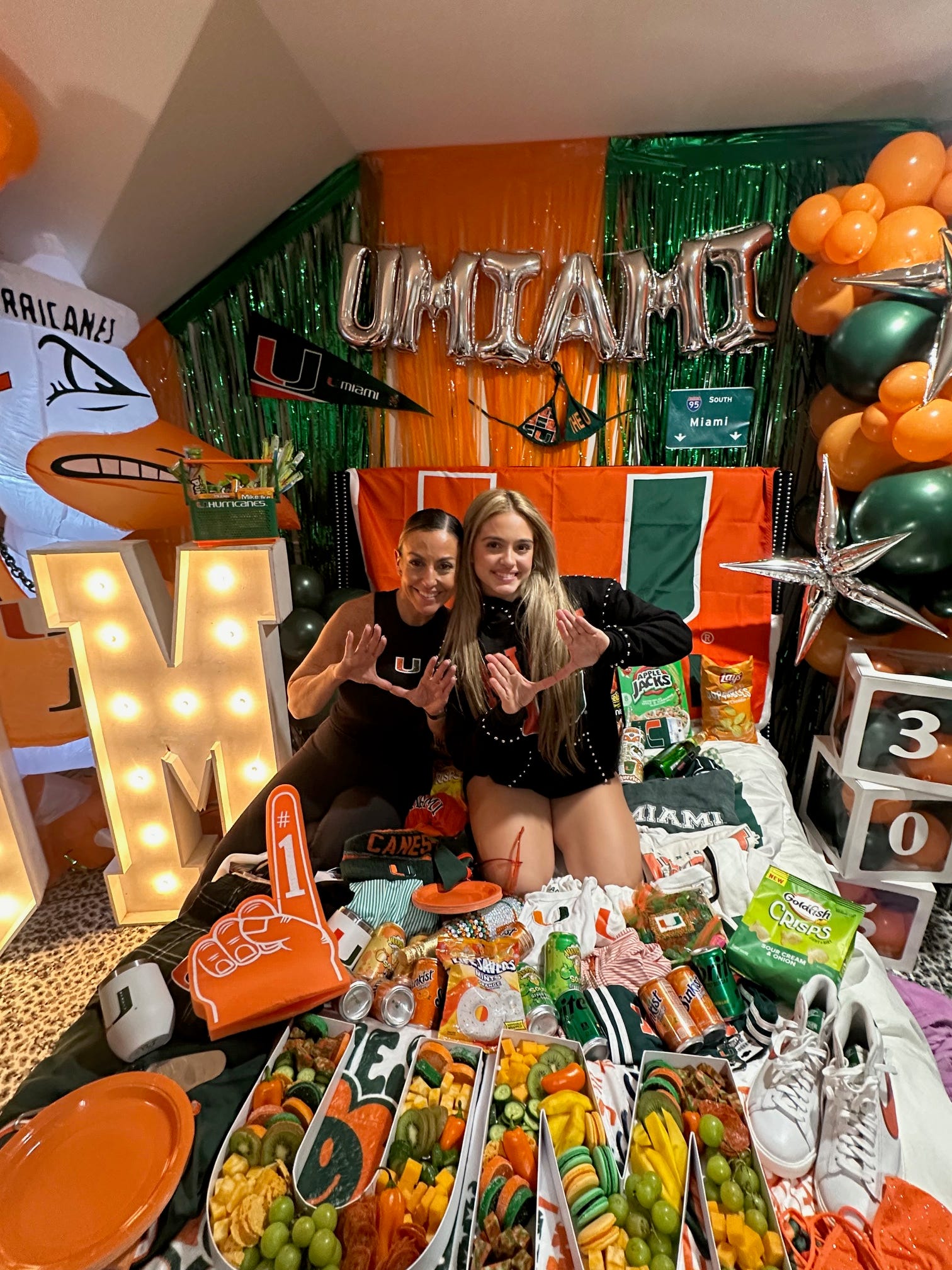 Melinda and Sienna posing with University of Miami colors and decor for the college bed party.