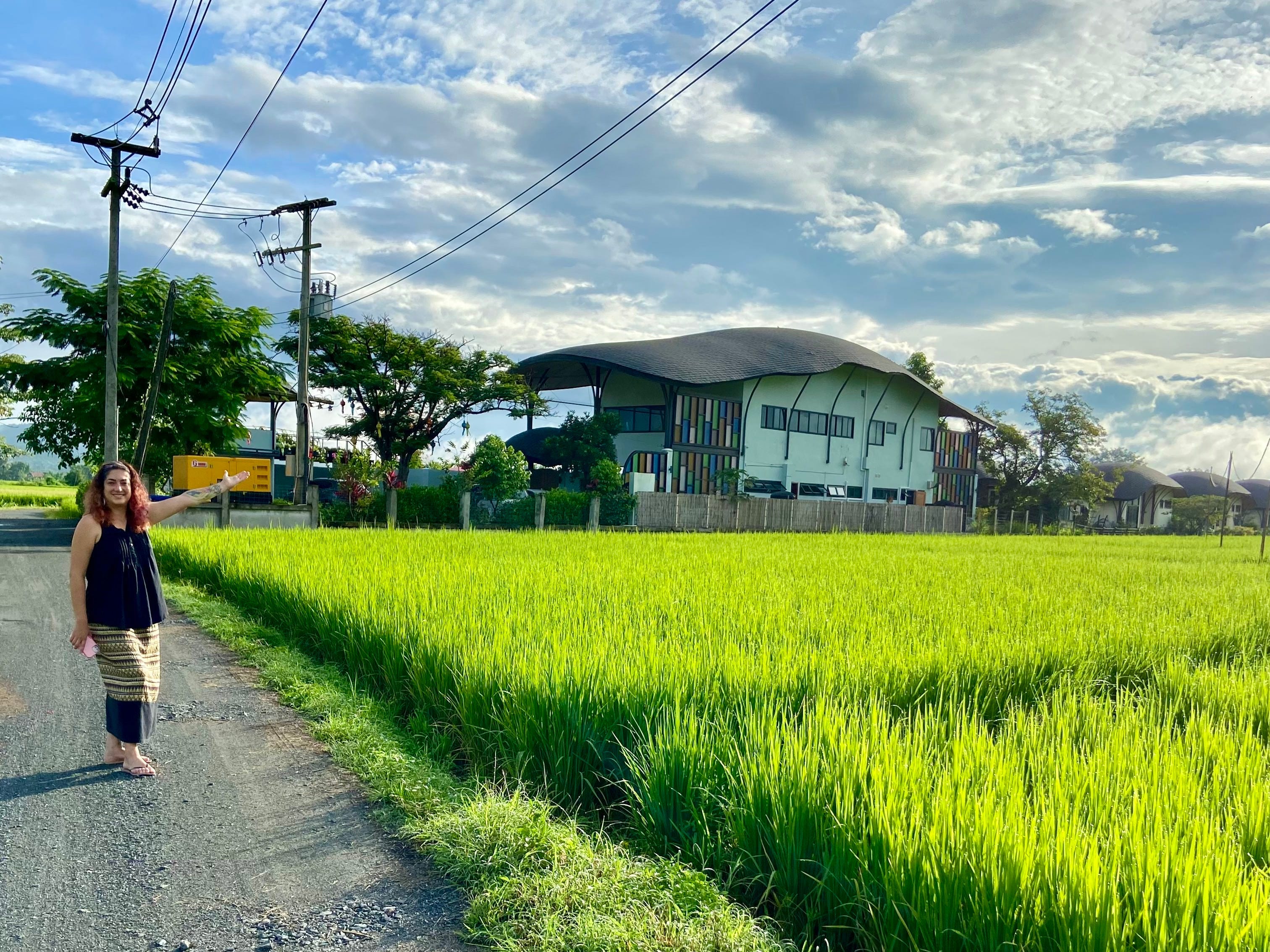 A woman standing beside a field of grass and the hotel.