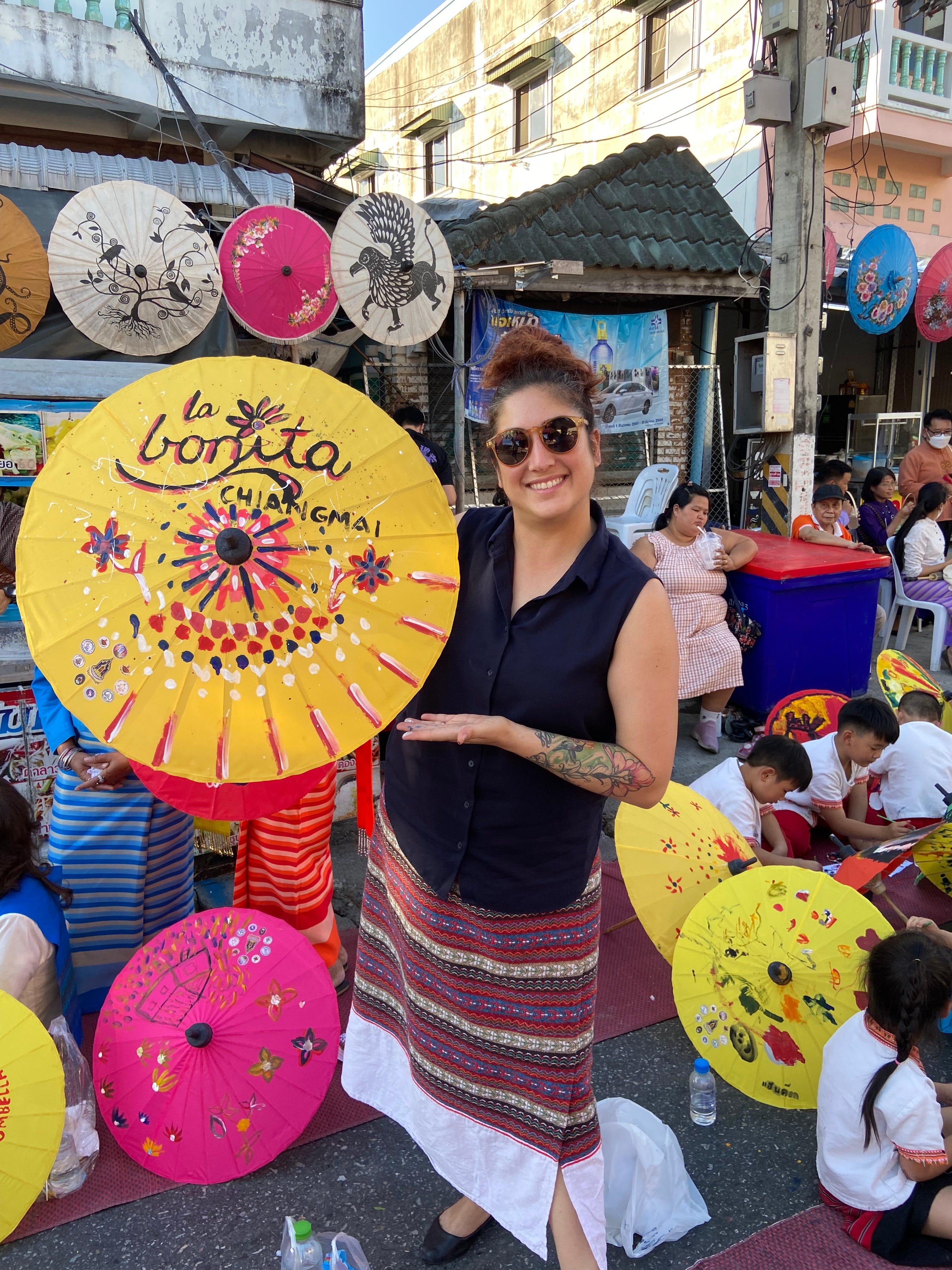 A woman holding a fan she painted.