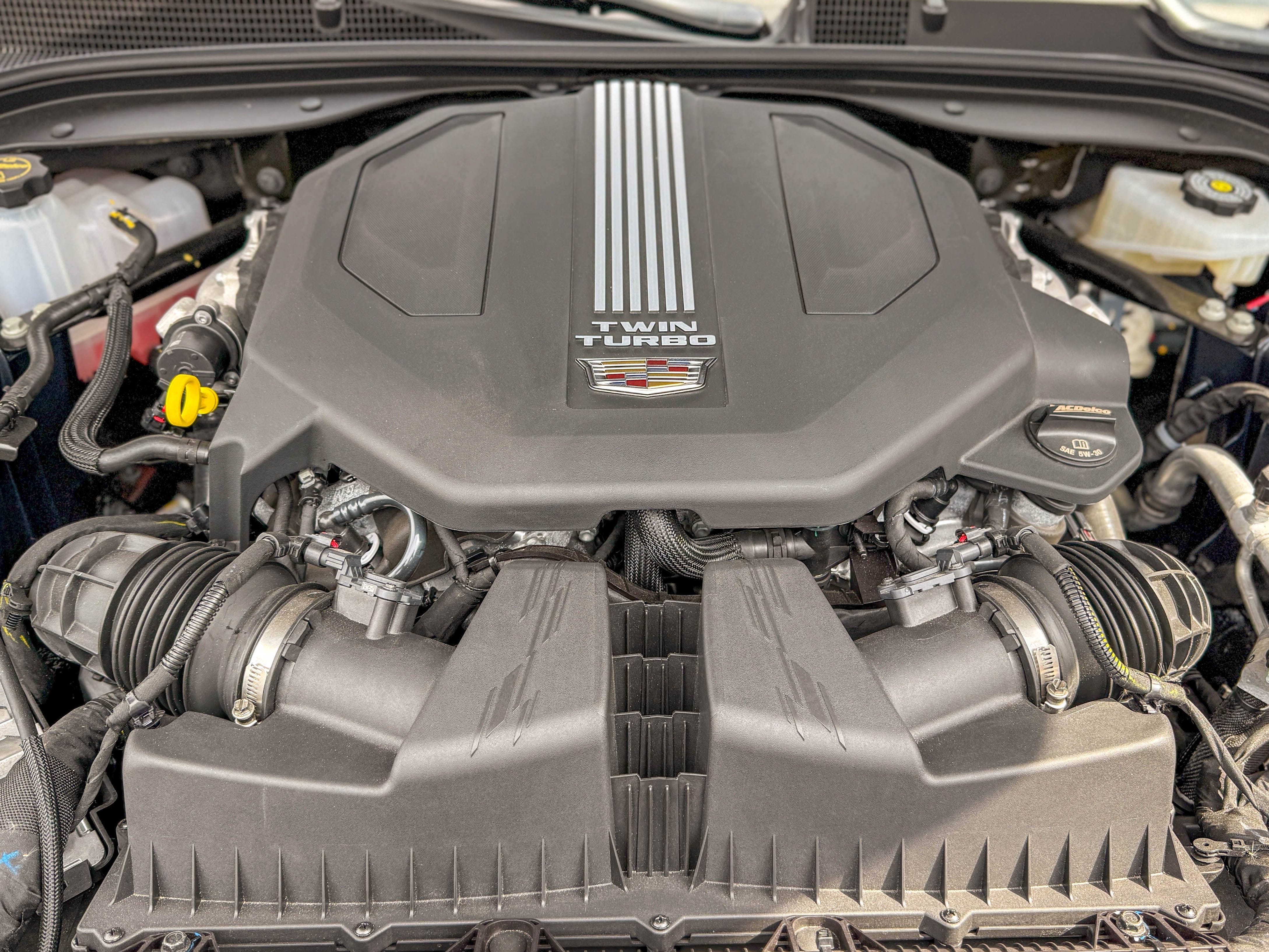 The 3.0-liter, twin-turbocharged V6 engine under the open hood of a 2025 Cadillac CT5-V sports sedan.