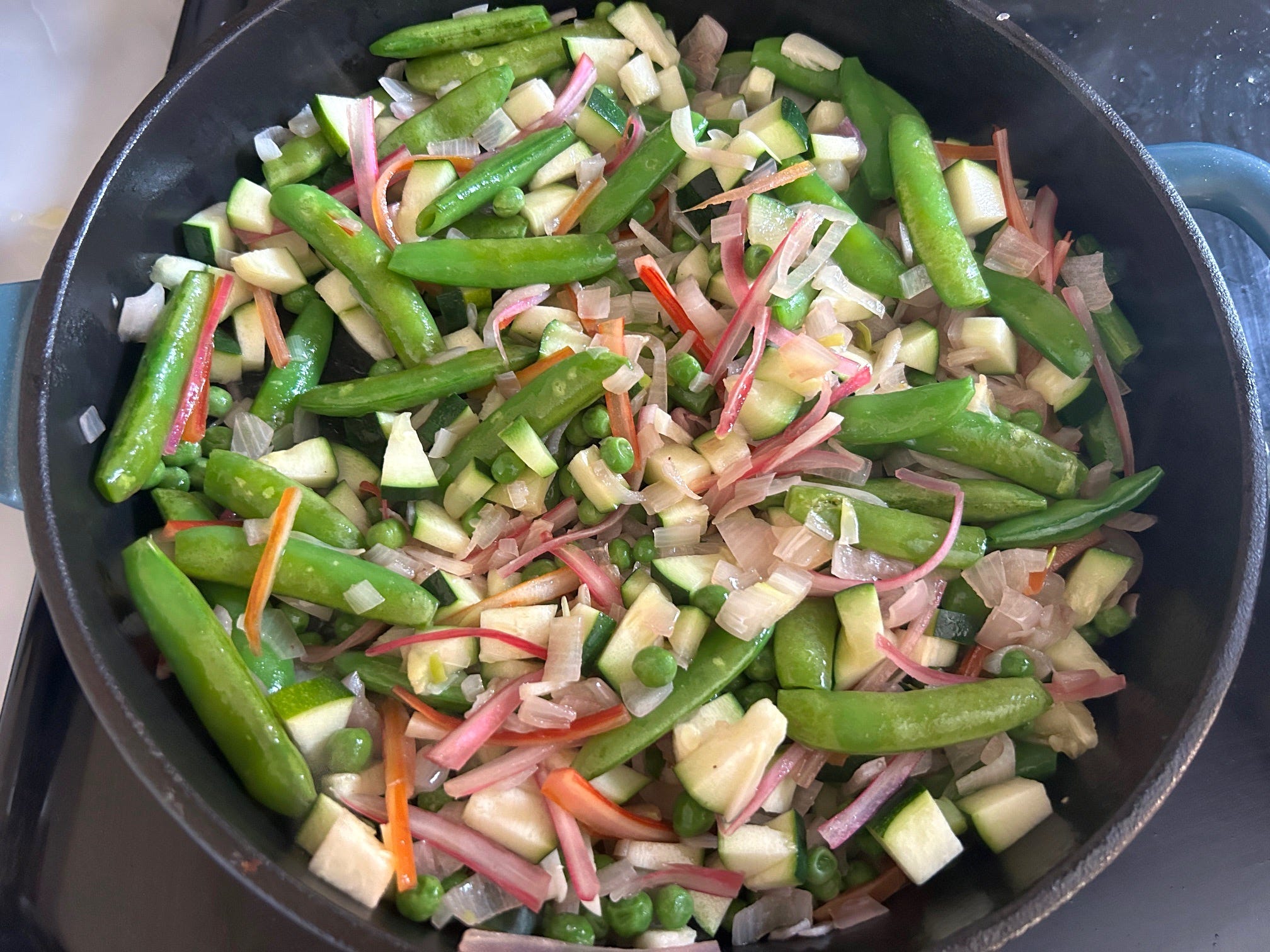 Cooking veggies in pan for Meghan Markle's spring garden pasta salad