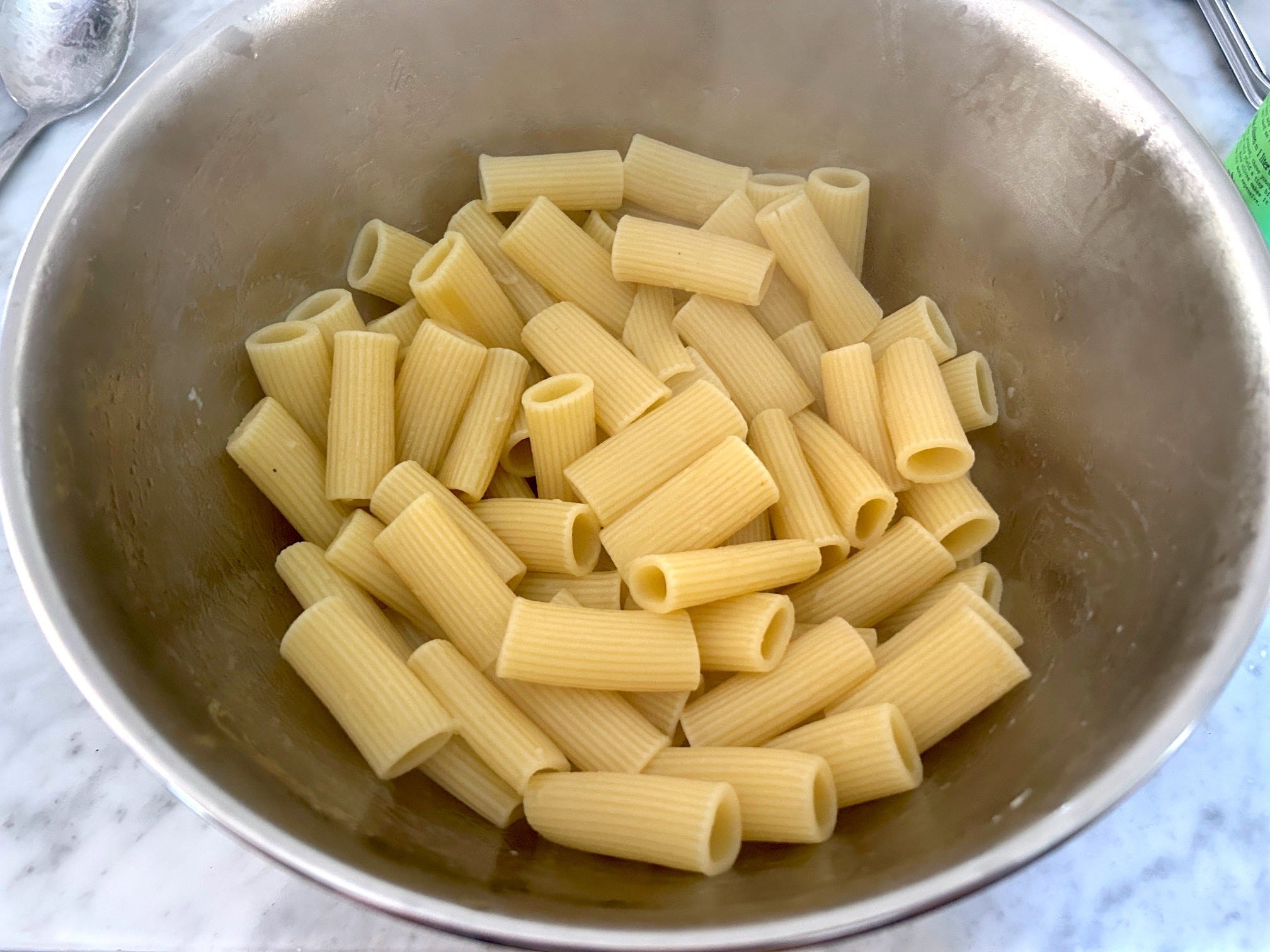 Adding olive oil to pasta for Meghan Markle's spring garden pasta salad