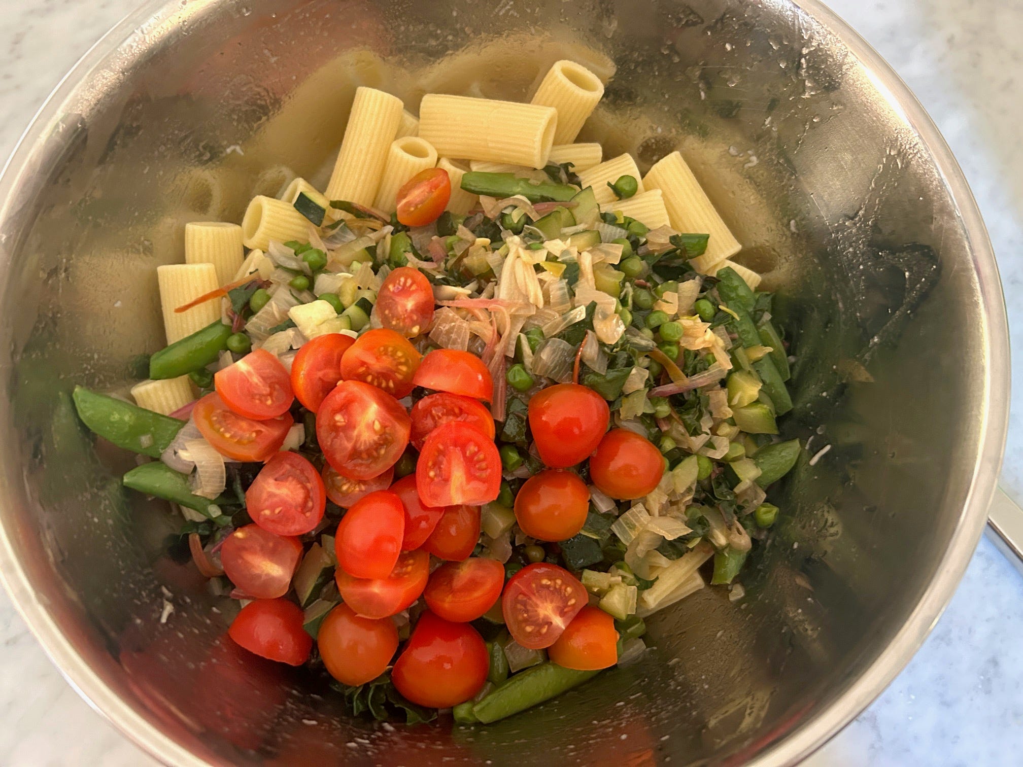 Adding cooked veggies to pasta for Meghan Markle's spring garden pasta salad