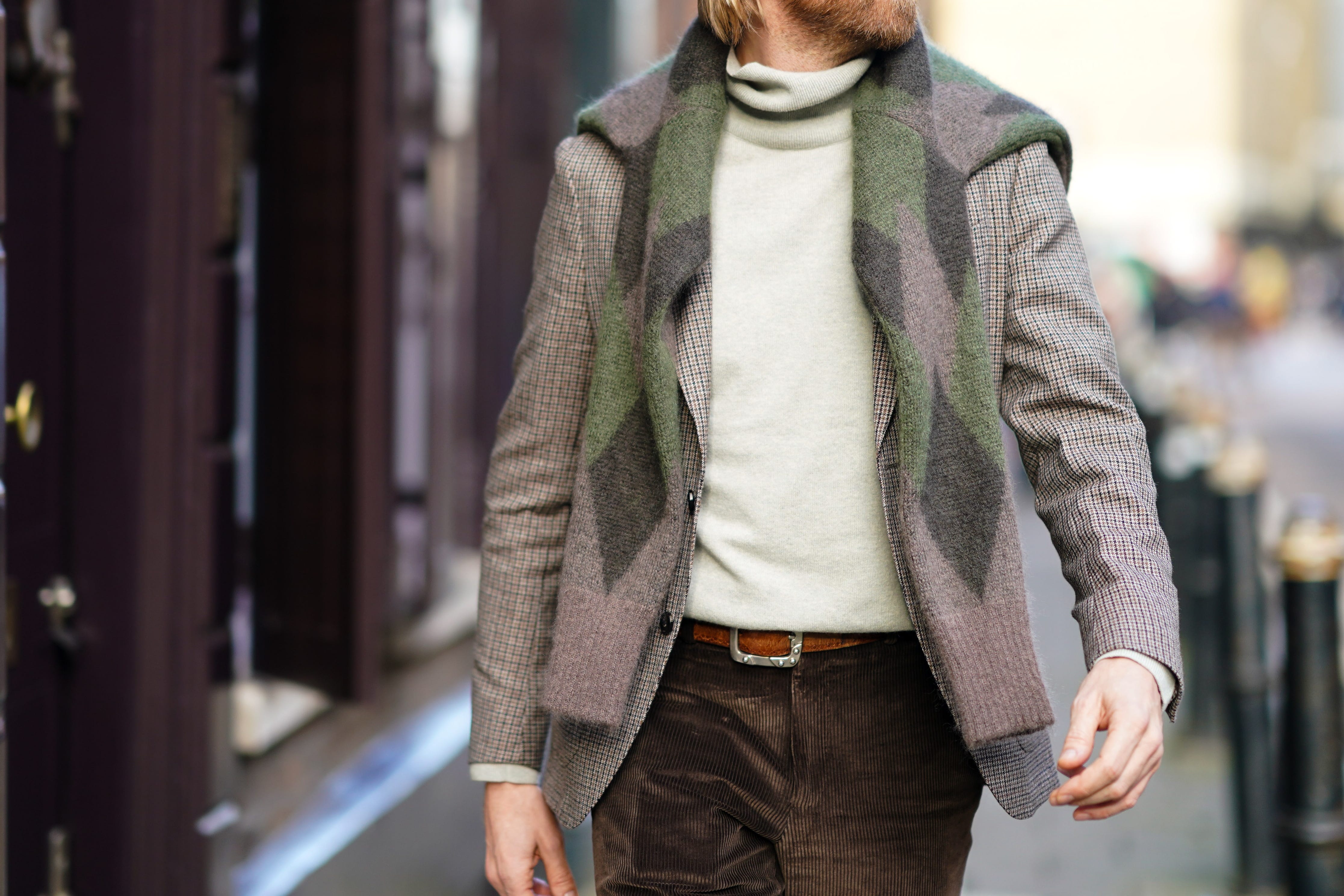 Man wearing newsboy cap, argyle knit sweater, suede pants