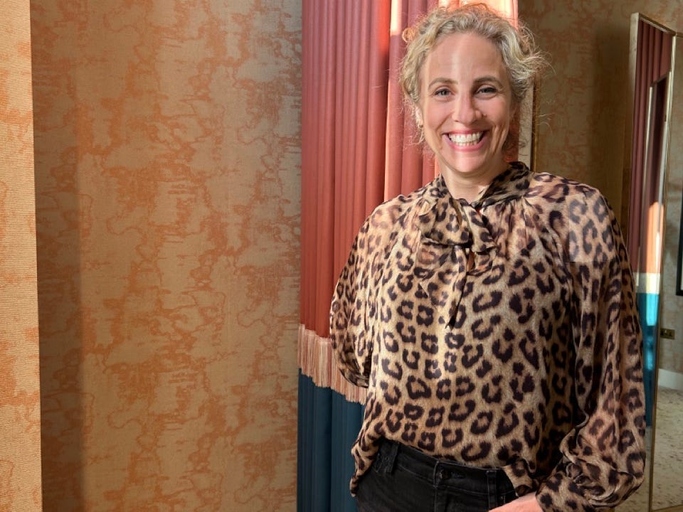 Author Alesandra Dubin smiling in animal-print shirt in brown tones