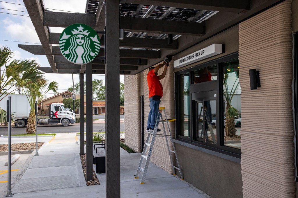 A construction worker adjusts a speaker at a 3D printed Starbucks building Monday, April 28, 2025, in Brownsville, Texas.