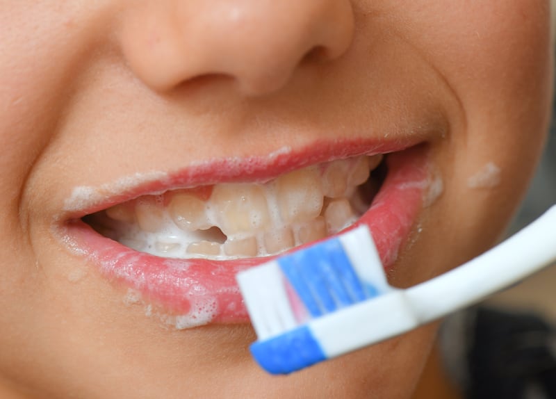 A girl brushes her teeth with toothpaste.
