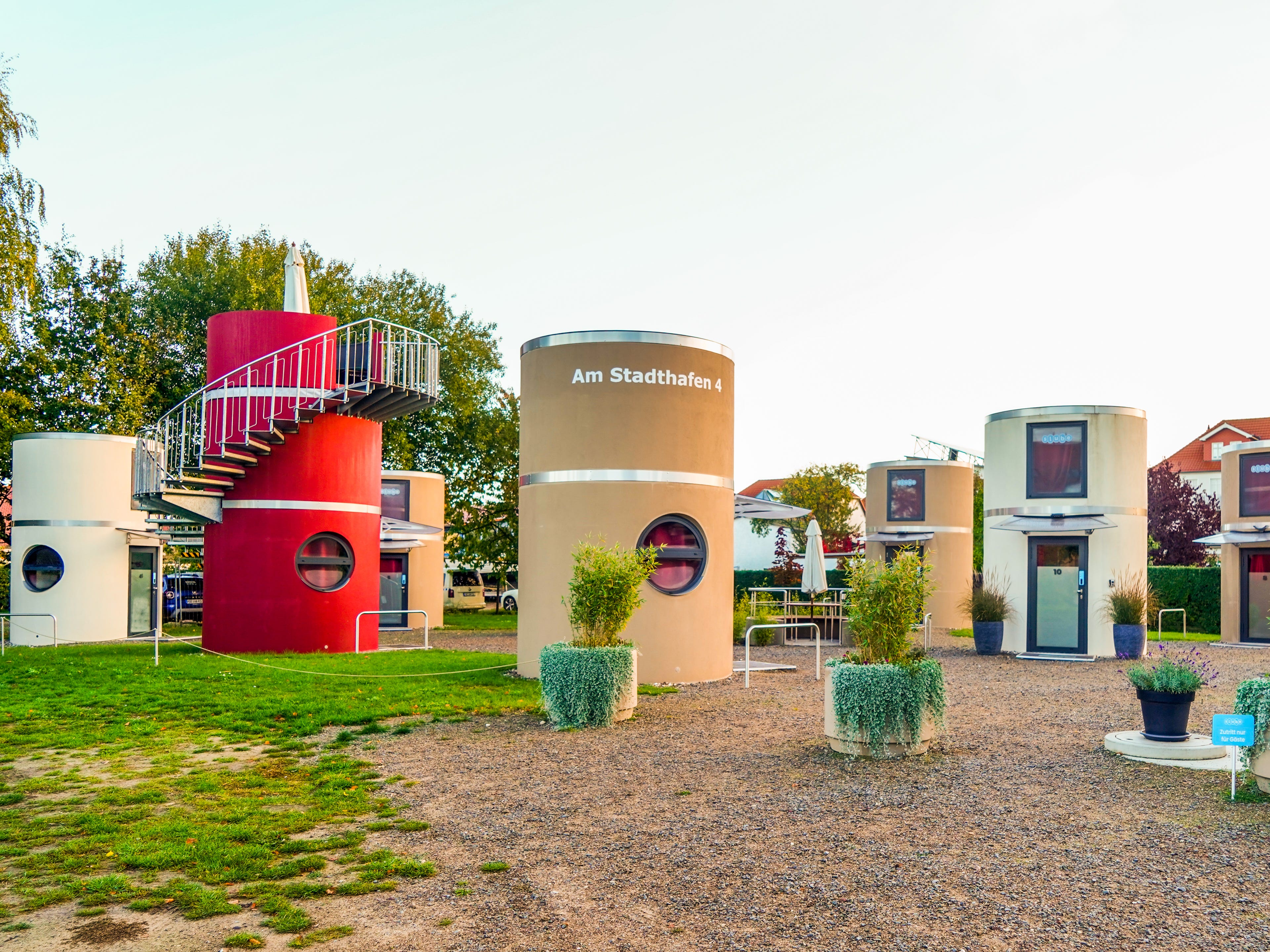 Several cylindrical homes on a flat property with grass on the left and gravel on the right
