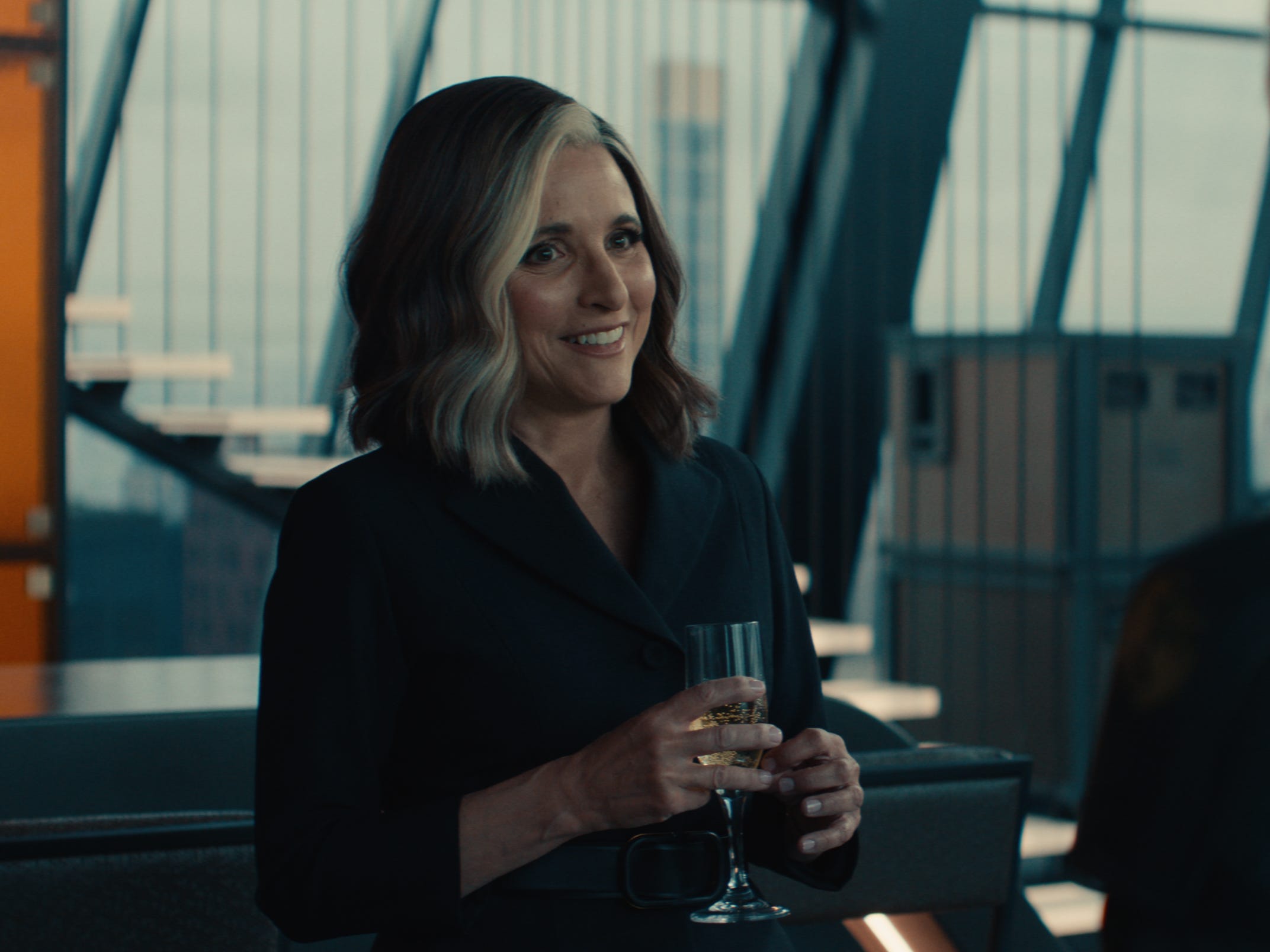 A still of "Thunderbolts*" showing Julia Louis-Dreyfus with white streaked hair holding a glass of bubbly.