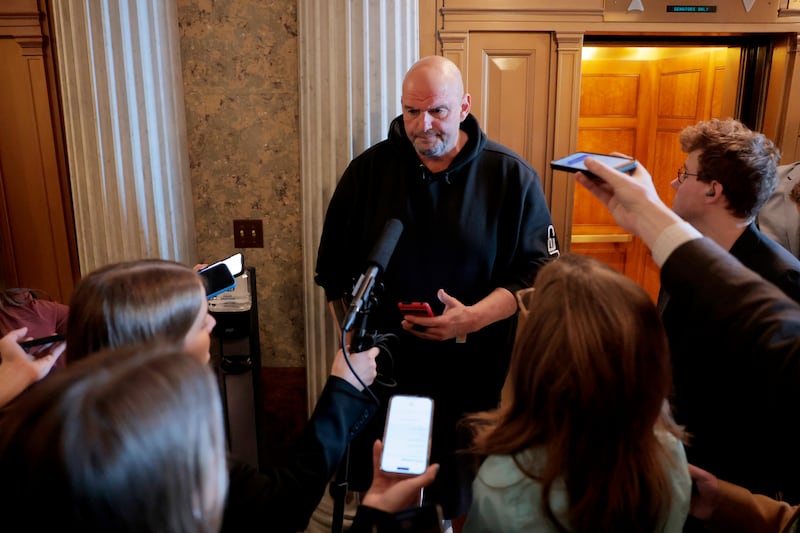 Senator John Fetterman, pictured speaking to reporters on March 13, still uses his phone to transcribe conversations in real time to help with auditory processing issues stemming from a stroke in 2022.
