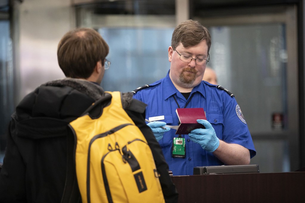 Transportation Security Administration agent checks a flyer through security.
