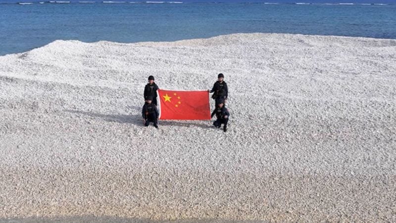 chinese coast guard holding chinese flag on sandy cay