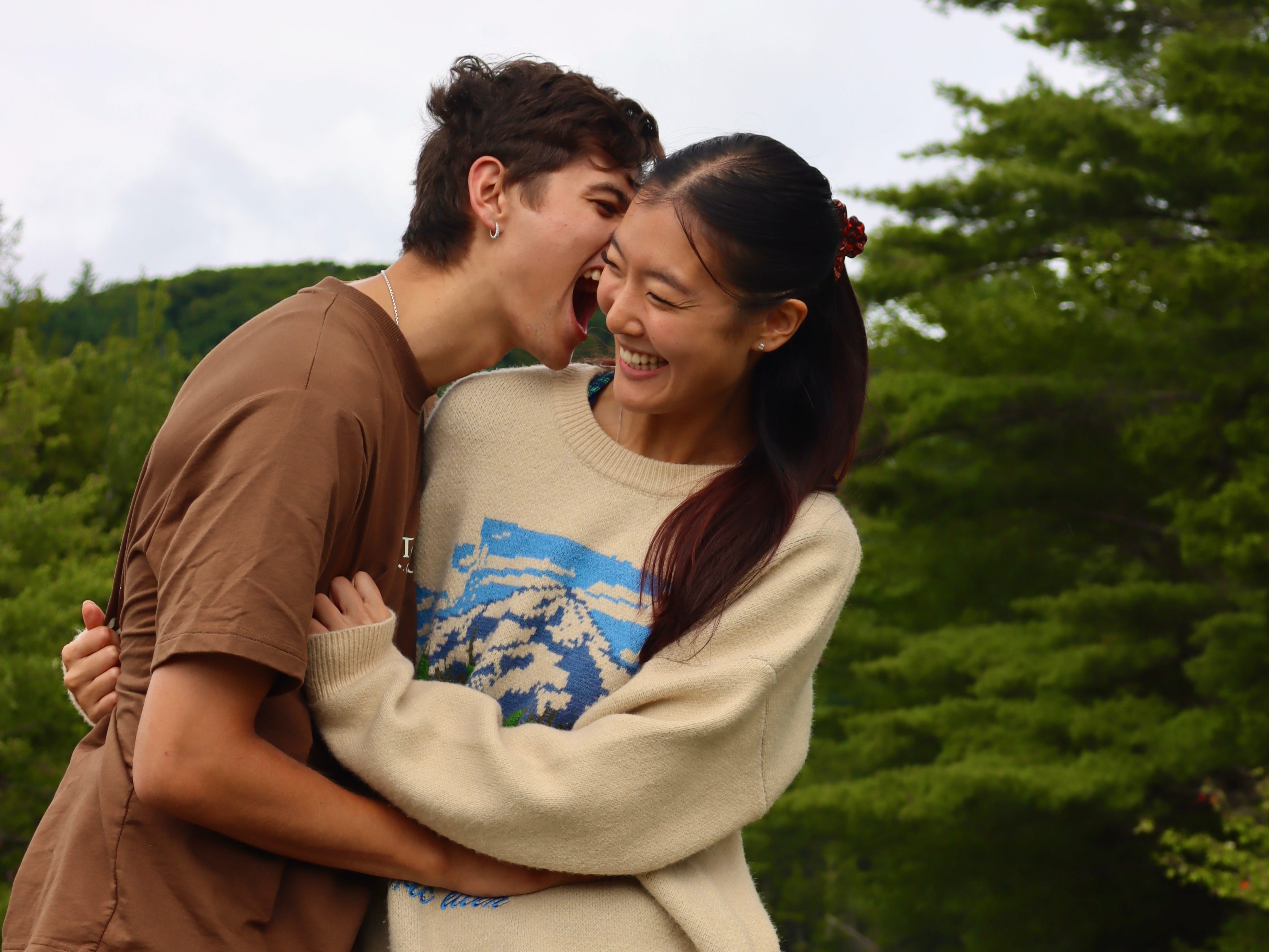 The author and her boyfriend standing outside in front of trees laughing.