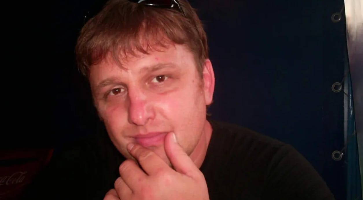 Vladyslav Yesypenko with hand on chin in front of black background