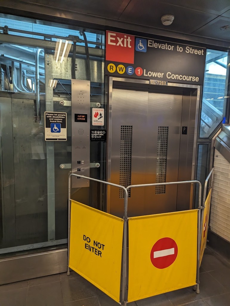 A yellow barrier that says do not enter placed in front of an out of service elevator in the subway