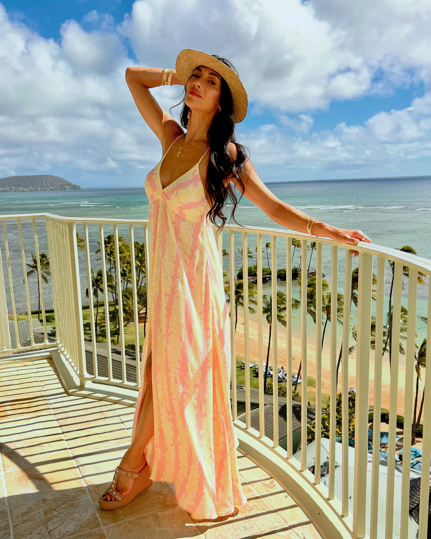 Nicole Scherzinger in a dress and hat by the beach. 