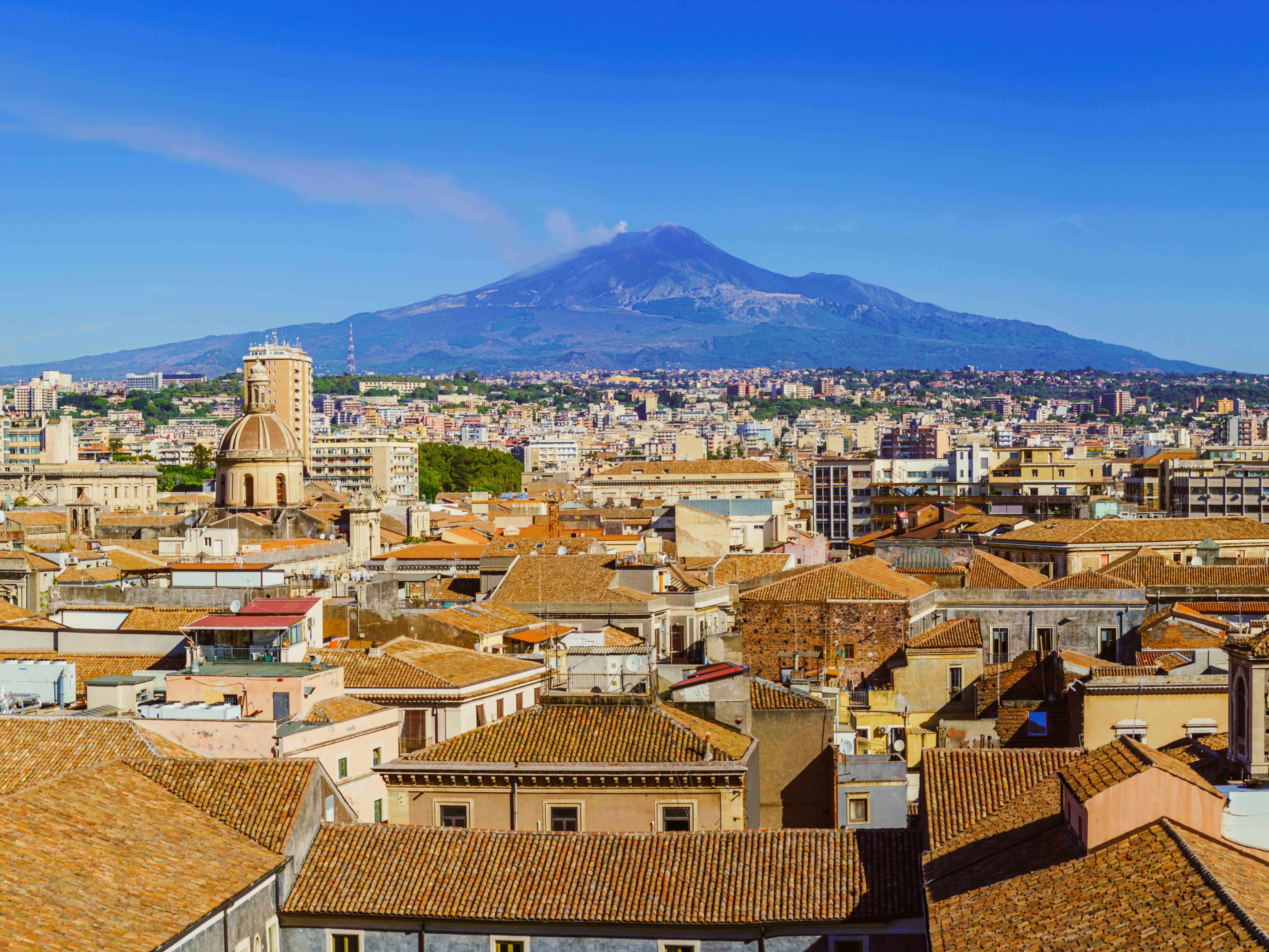 An Italian city with Mount Etna in the distance.
