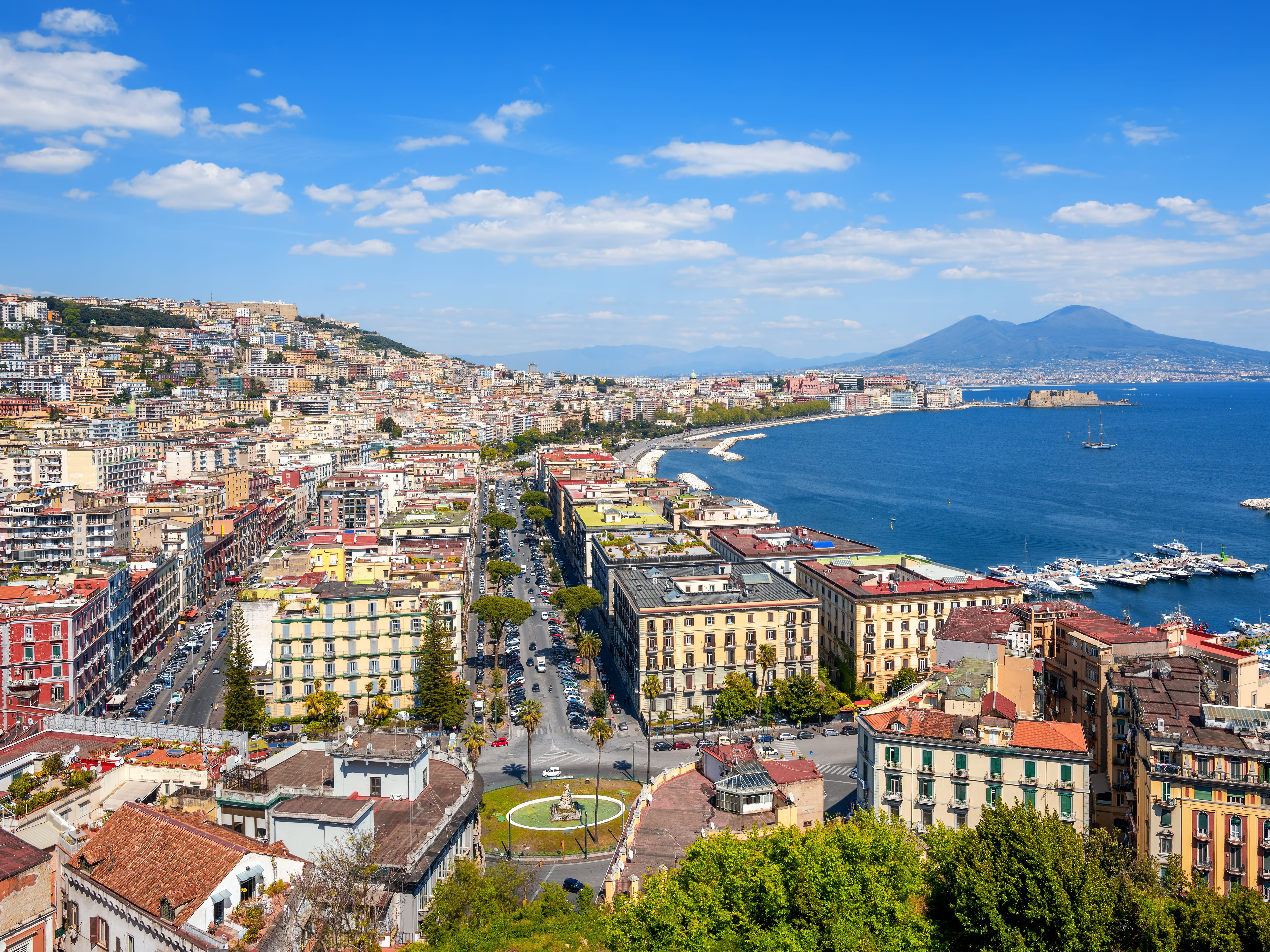 A city near the water, with a volcano in the distance.