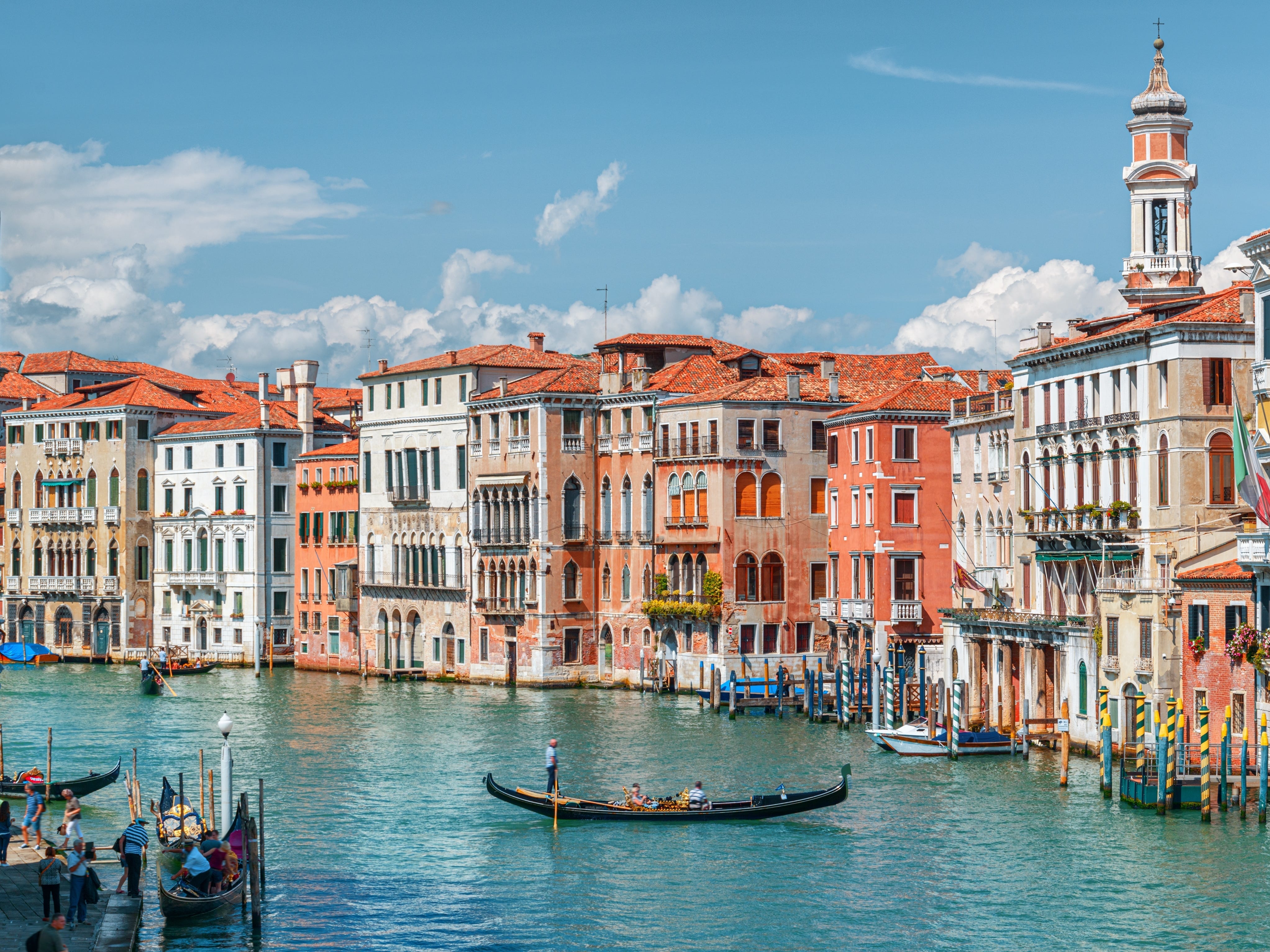 Gondolas in the water next to colorful buildings lining the canal.