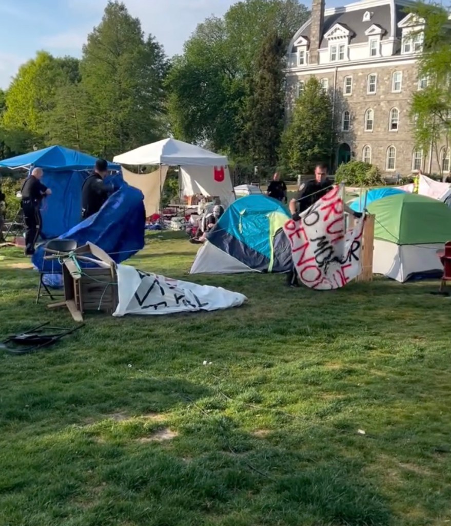 Tents and signs on the lawn being torn down by police