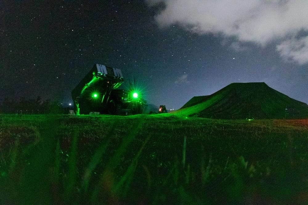 A NMESIS weapon system is illuminated by green lights at night