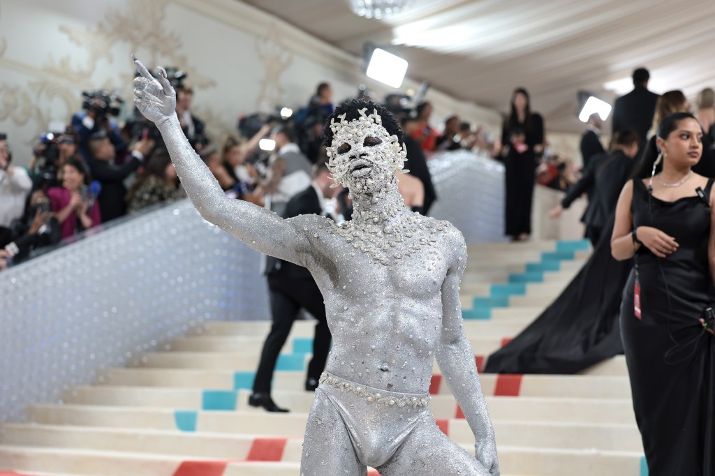 Lil Nas X on the red carpet of the 2023 Met Gala wearing silver spray paint and decked in crystals. 