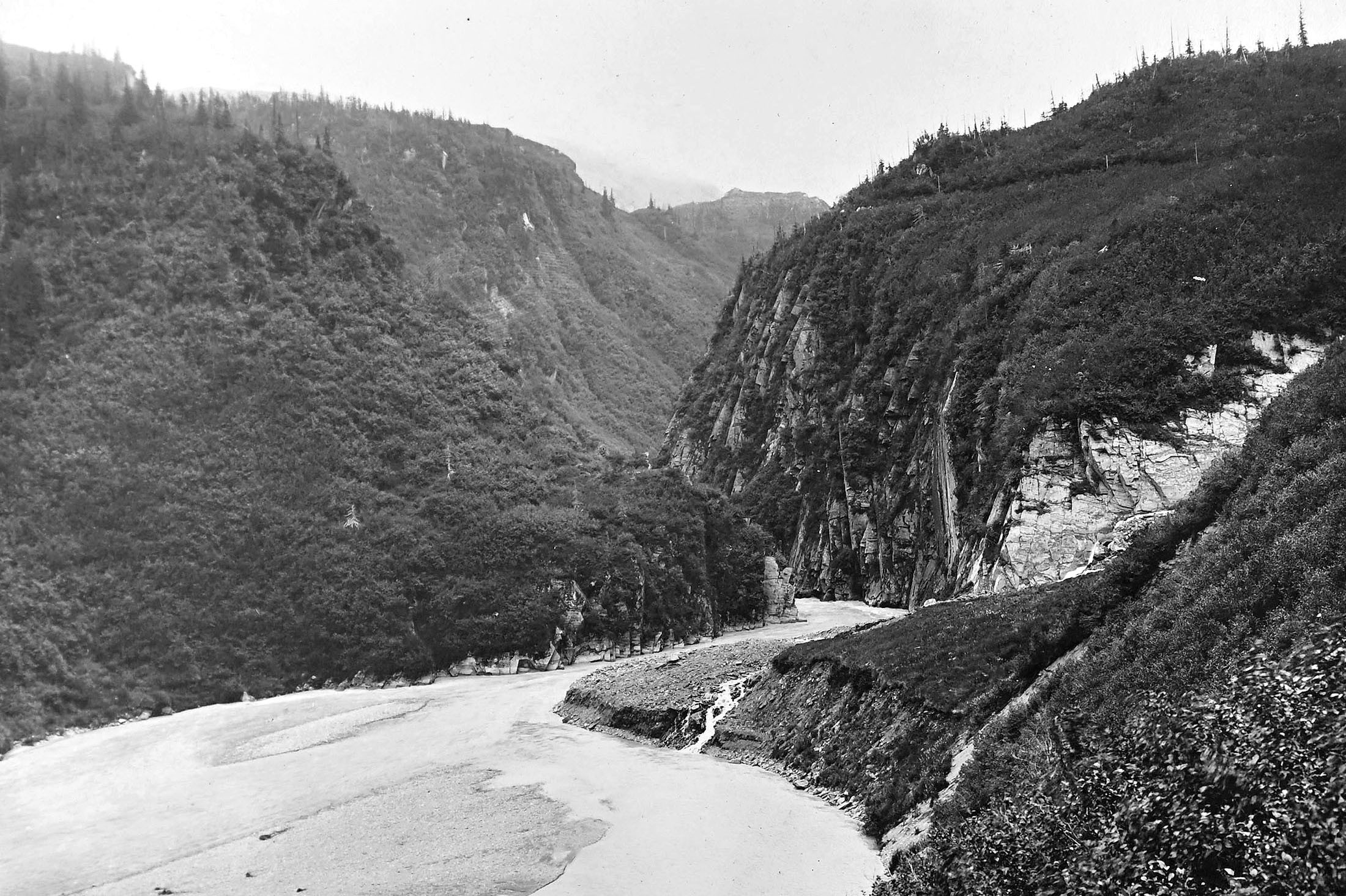 A steep-walled and narrow canyon, with a river running along its base.
