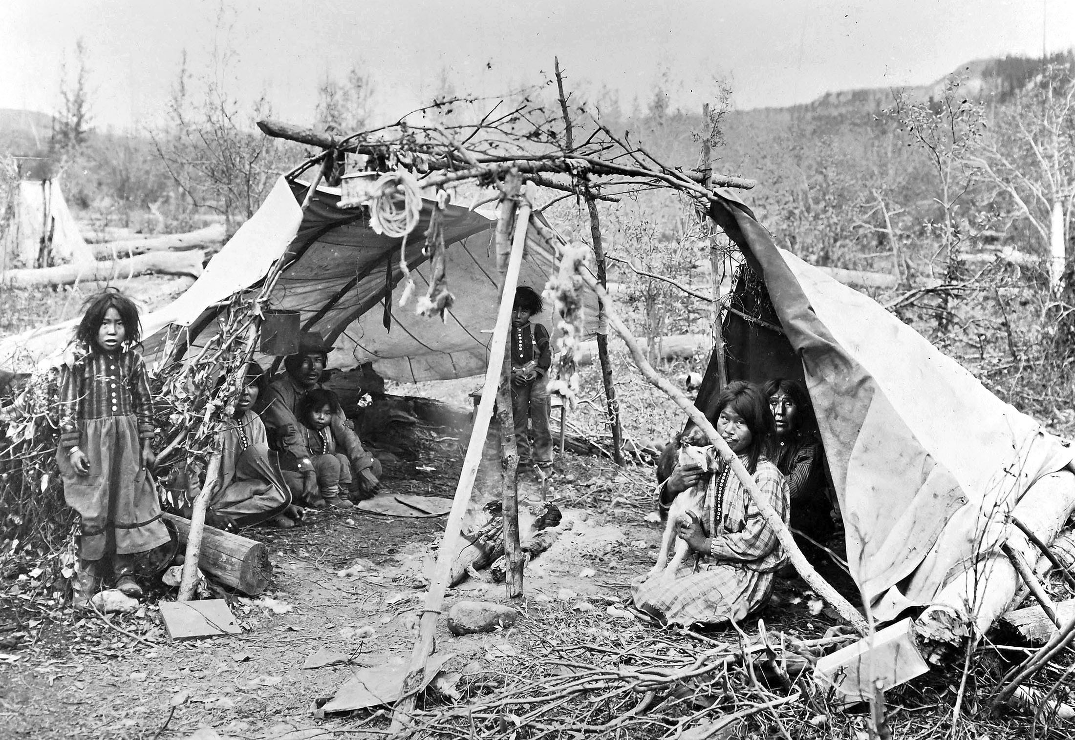 A family of Alaska Natives sit together inside a shelter.