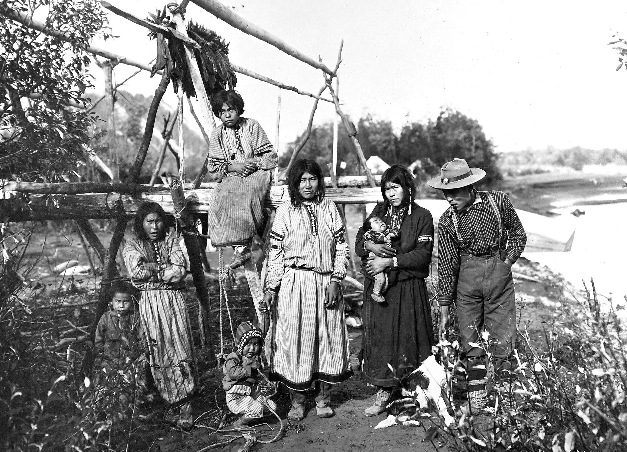 A family of Alaska Natives stand for a photograph, alongside a river.