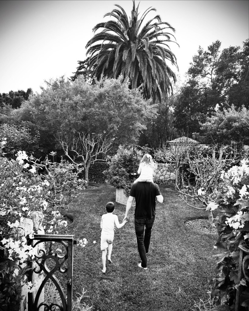 Prince Harry walking with his two kids, Prince Archie and Princess Lilibet, in a garden