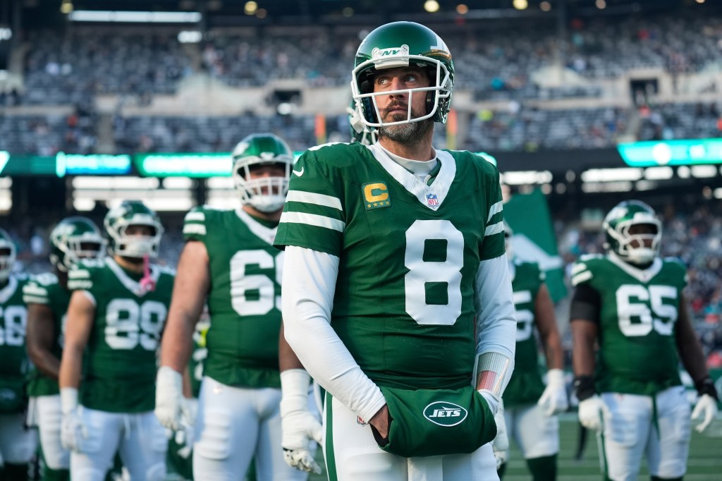 New York Jets quarterback Aaron Rodgers (8) stands with teammates before an NFL football game against the Miami Dolphins