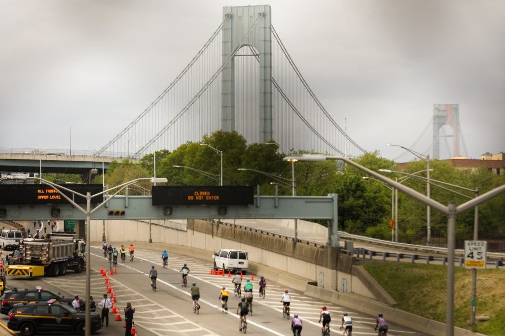 Thousands of people participating in the 5 Boro Bike Tour in New York City, transitioning from Brooklyn over the Verrazano Narrows Bridge into Staten Island.