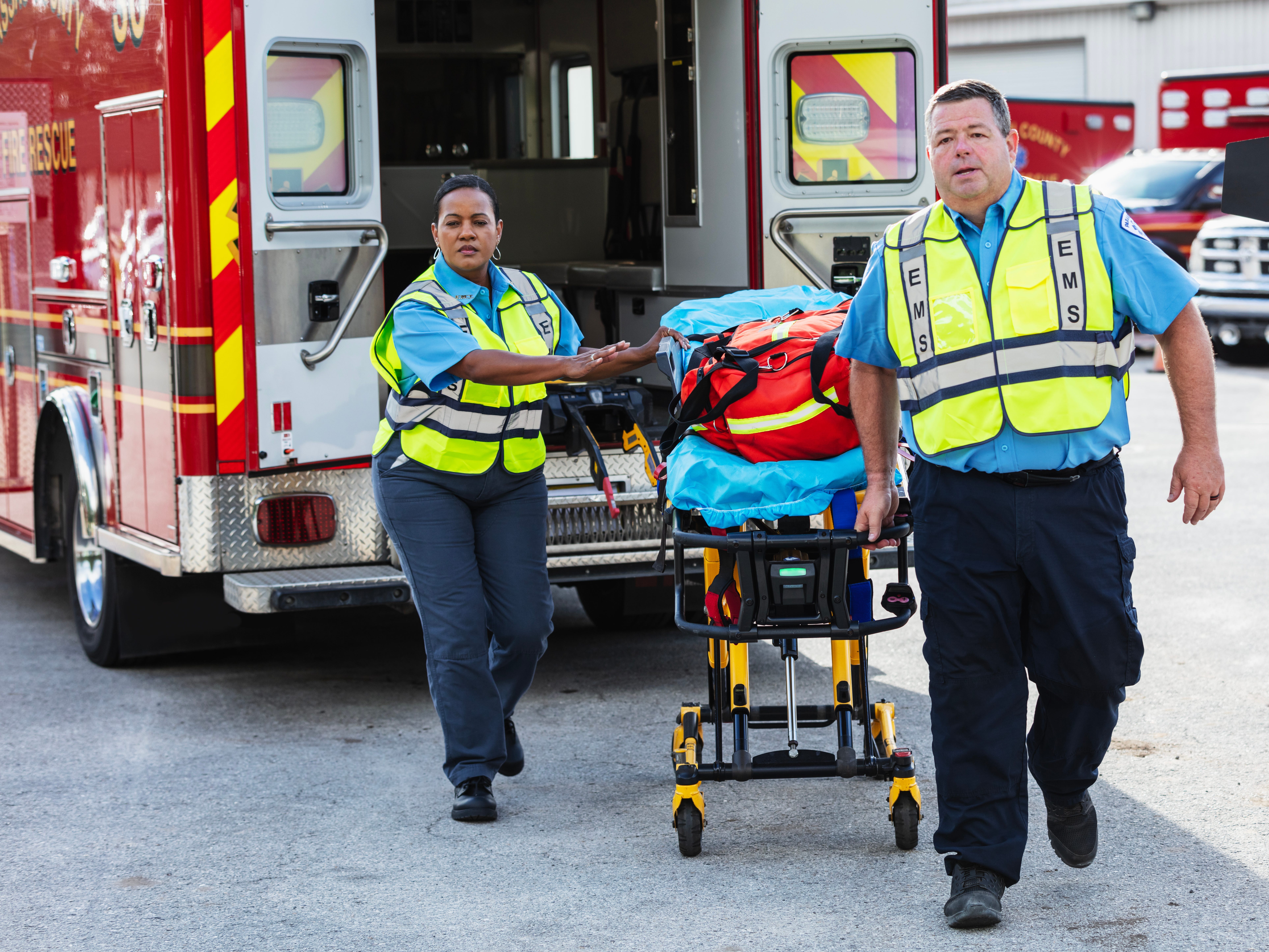 Two paramedics with a gurney by the back of an ambulance