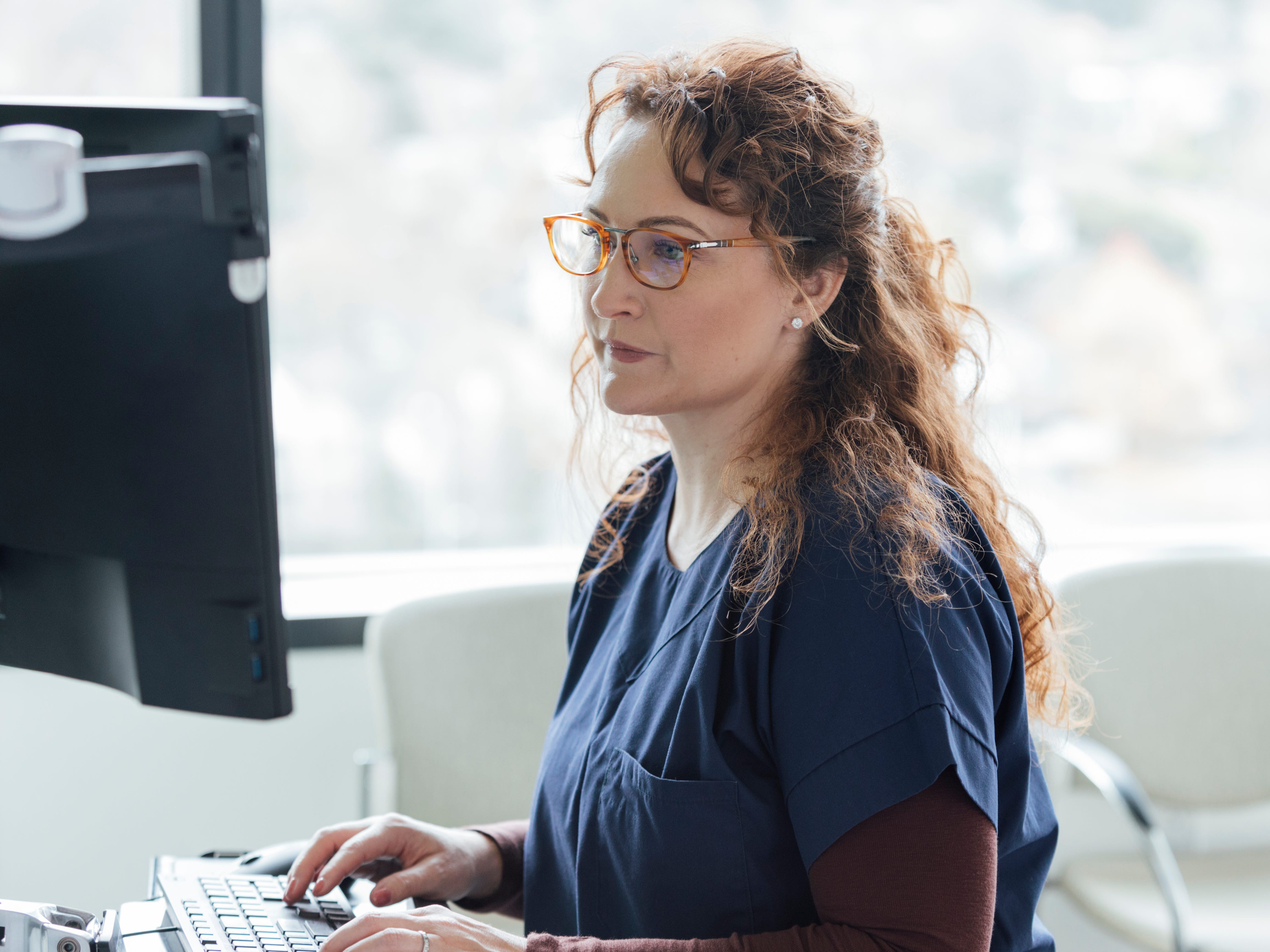 A healthcare worker typing on a computer keyboard