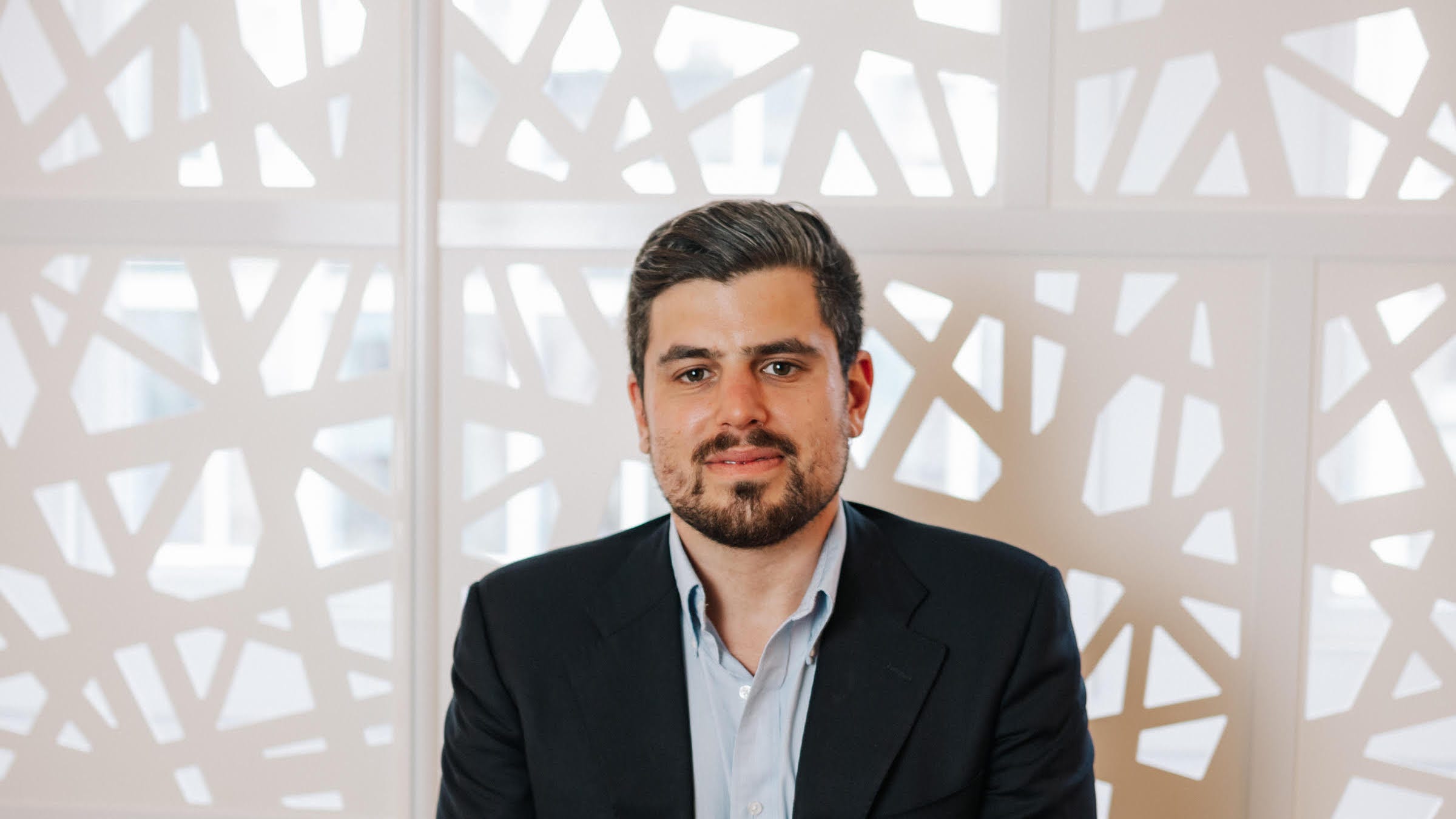 A man in front of a geometric screen.