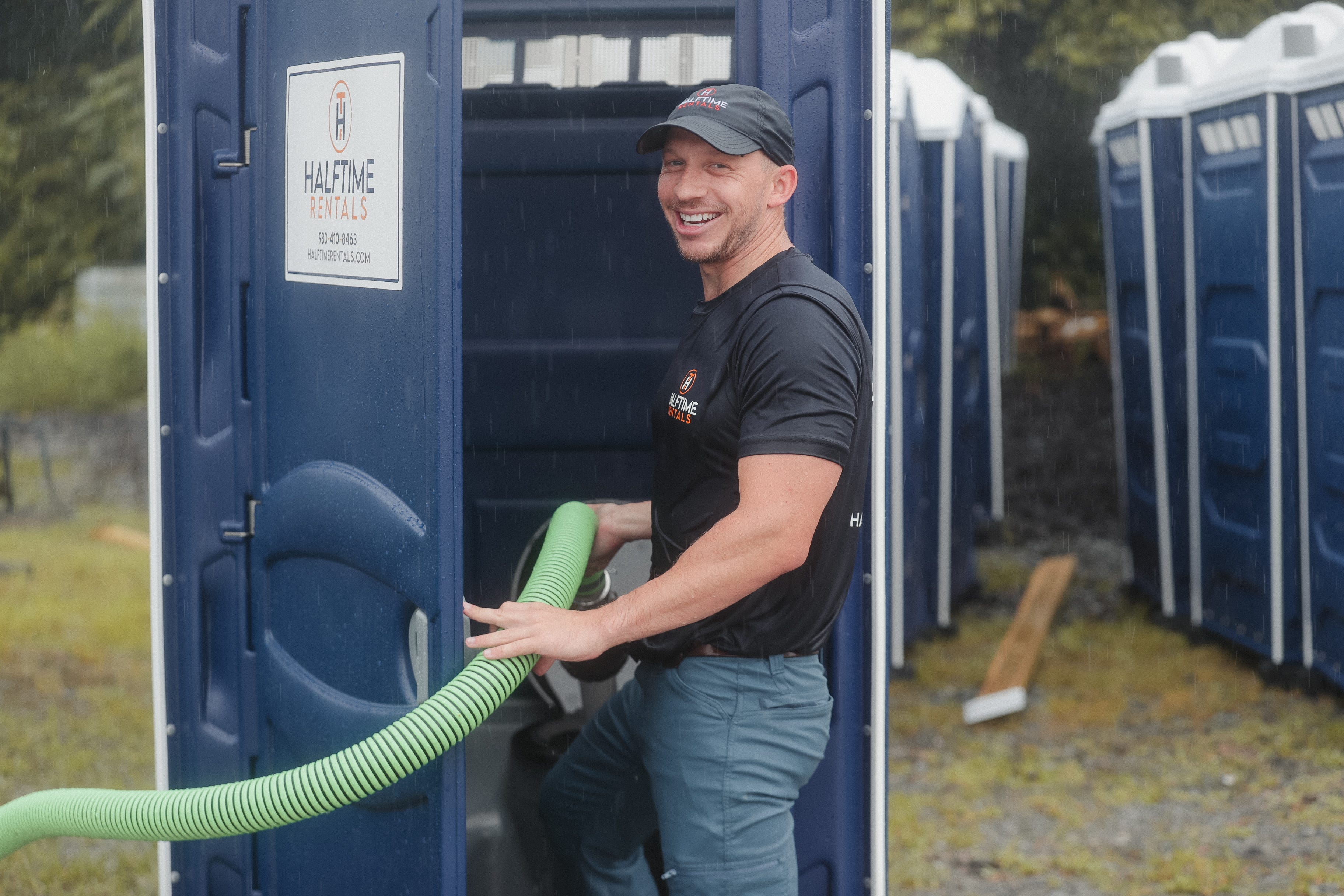 Man using hose to empty a portable toilet