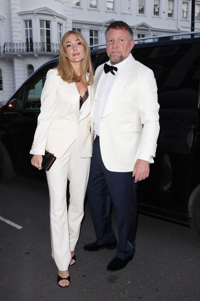 Guy Richie in a white tuxedo jacket, white shirt and black bow tie and black pants, Jacqui Richie in a white pant suit and black top.