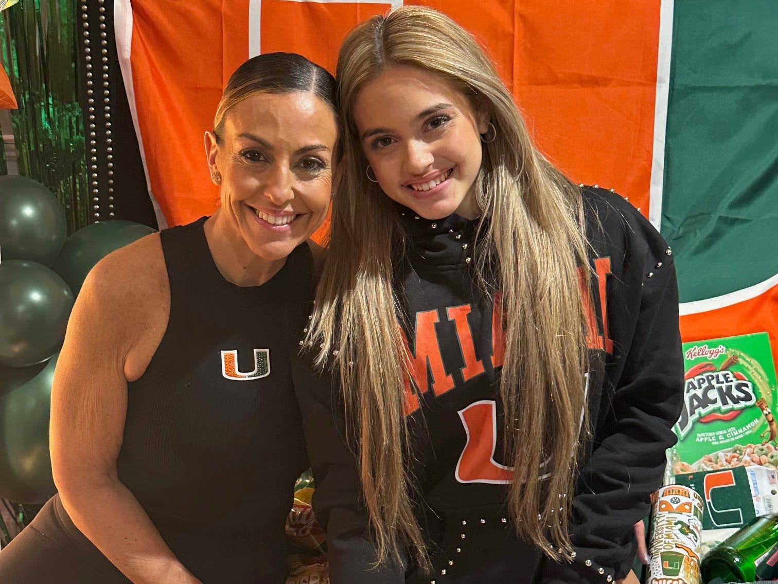 Melinda and Sienna posing in front of University of Miami college bed party decor.