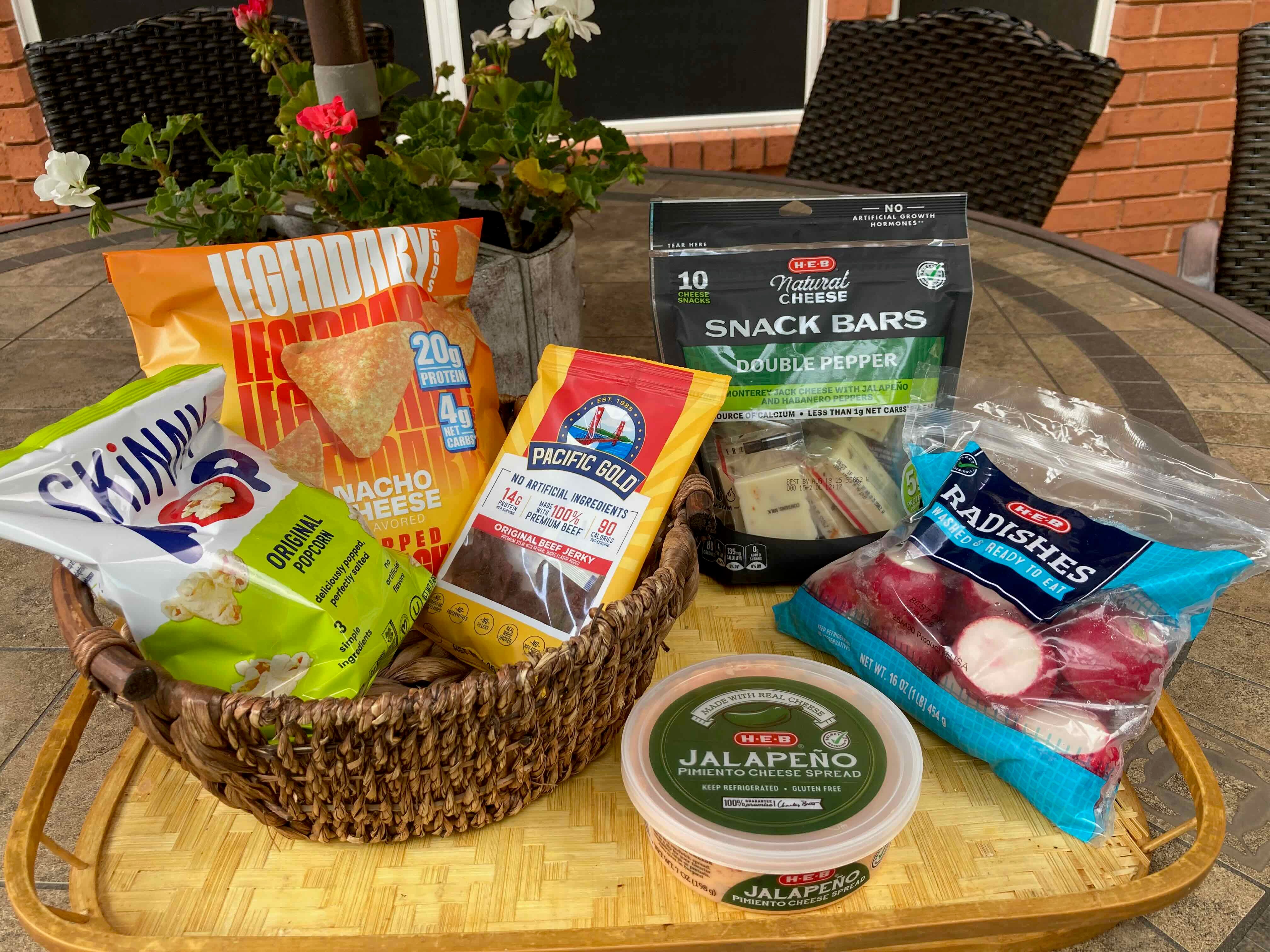 bag of skinny pop, beef jerky, cheese bars, radishes, and pimento cheese on a table