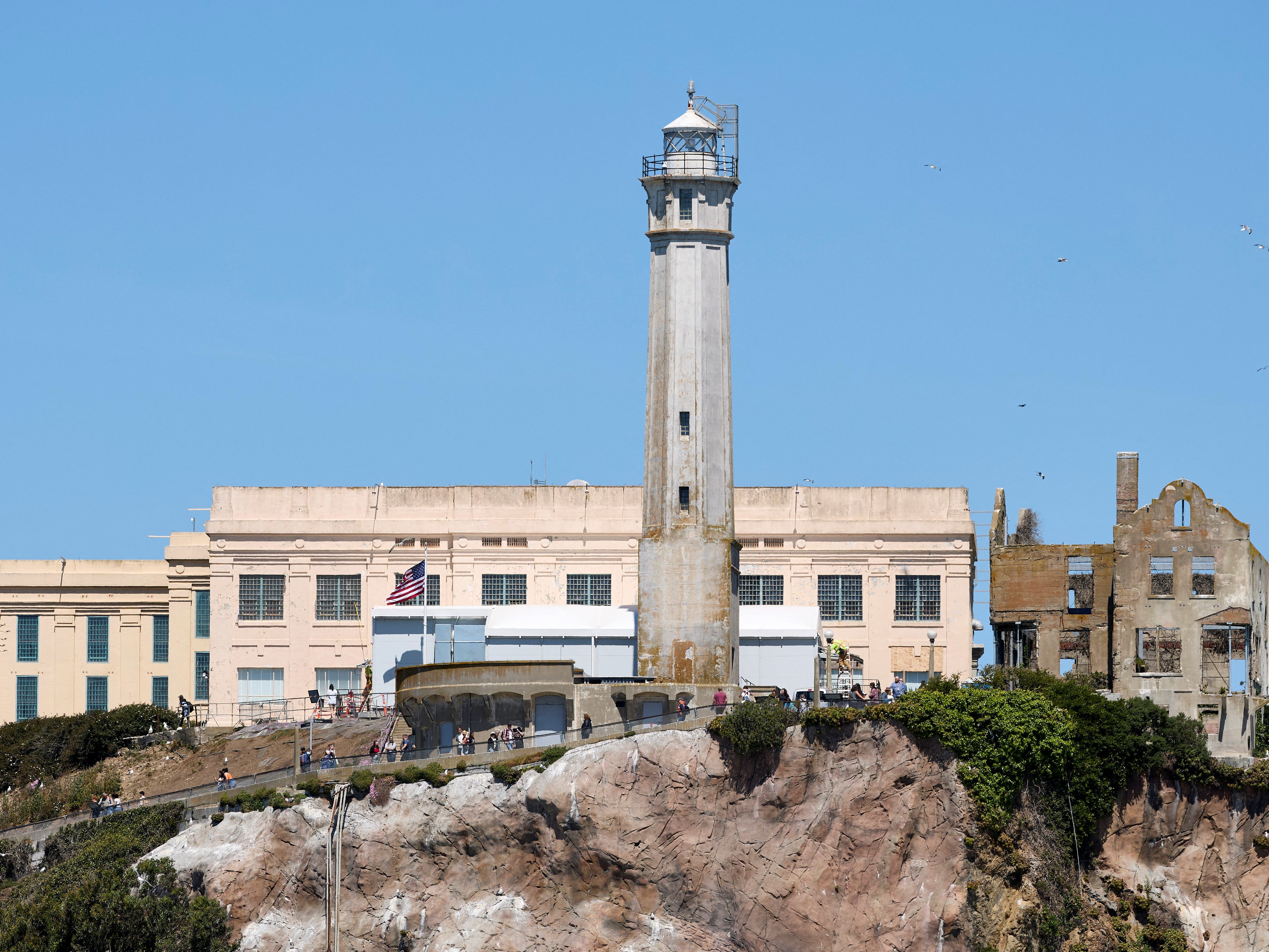 A lighthouse with a cream-colored building in the background